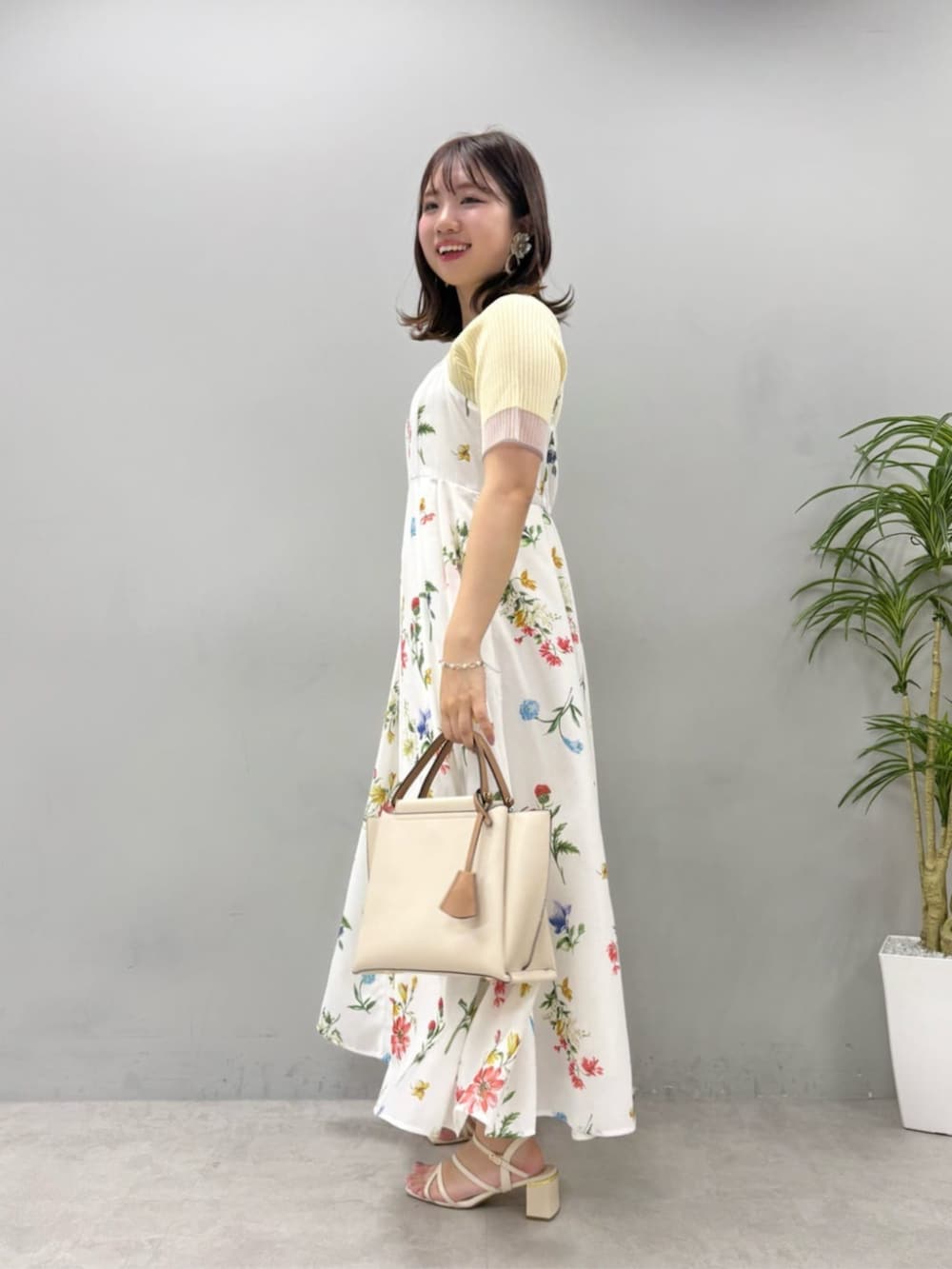 イエロー系のニット/セーター、ホワイト系のワンピースを着用したレディースの夏コーディネートの3枚目の写真