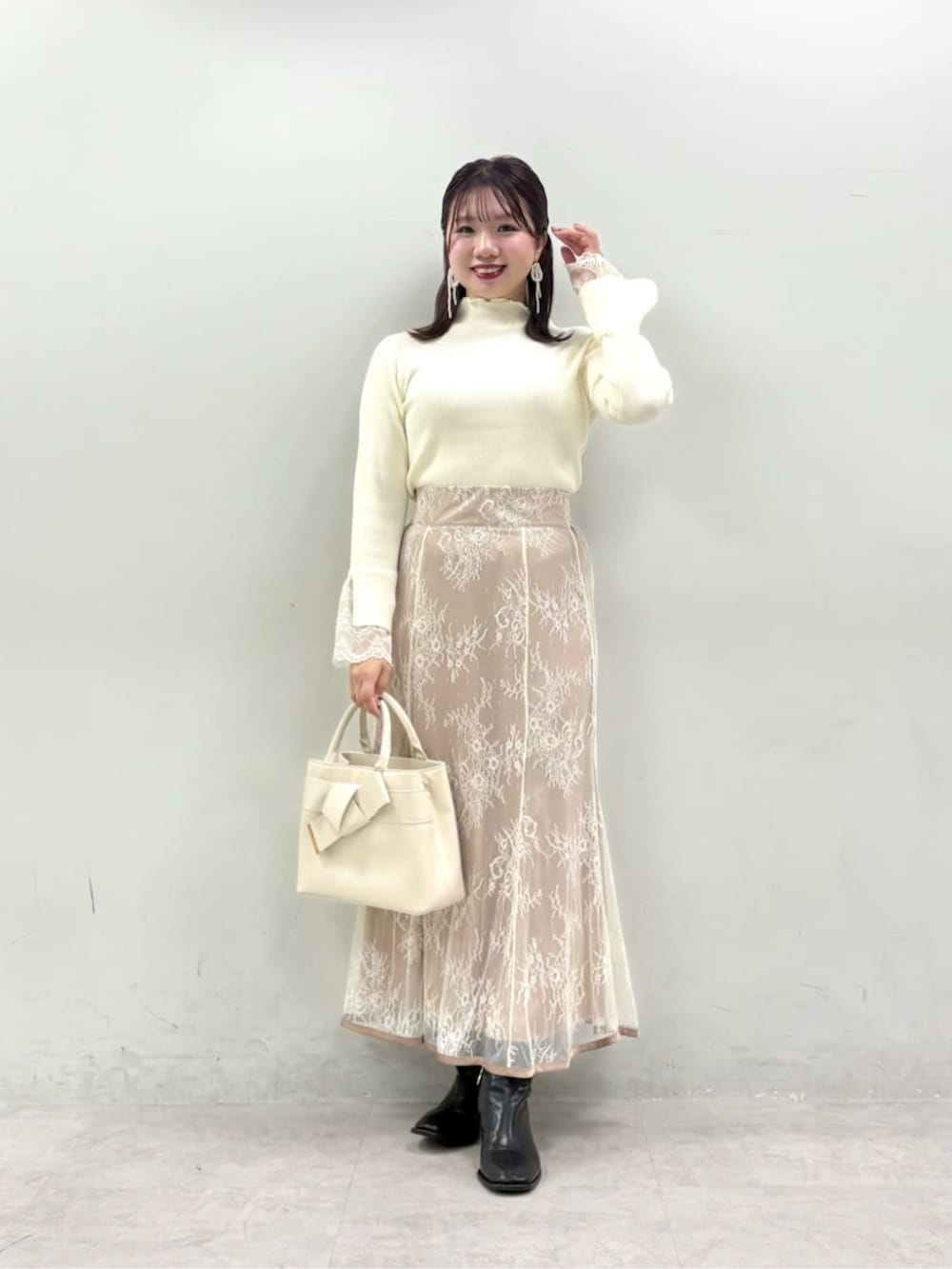ベージュ系のスカート、ホワイト系のニット/セーターを着用したレディースの夏コーディネートの2枚目の写真