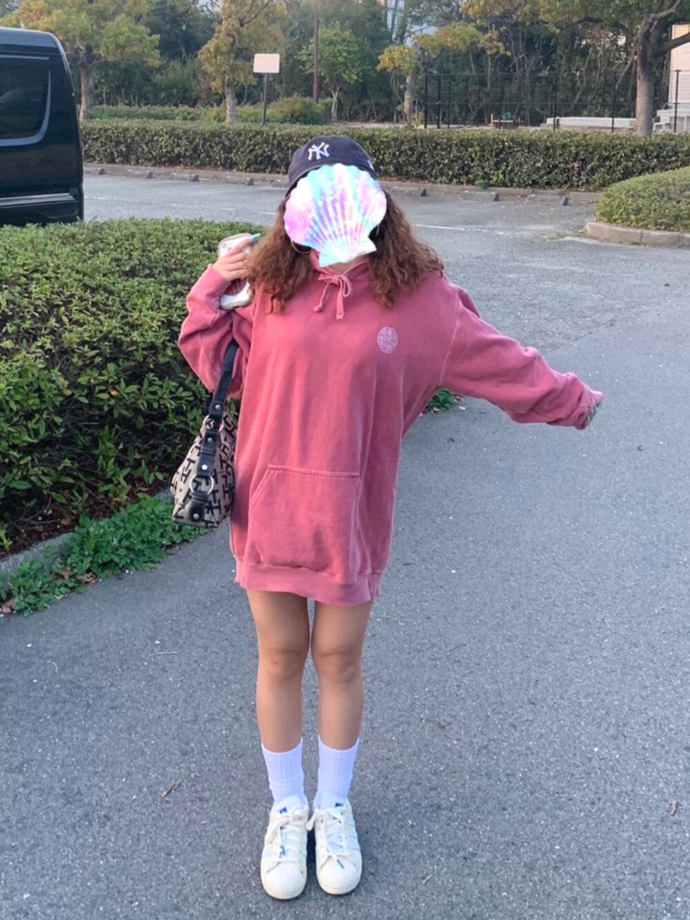 レッド系のパーカー、ベージュ系のバッグ、ホワイト系のスニーカーを着用したレディースの春コーディネートの2枚目の写真