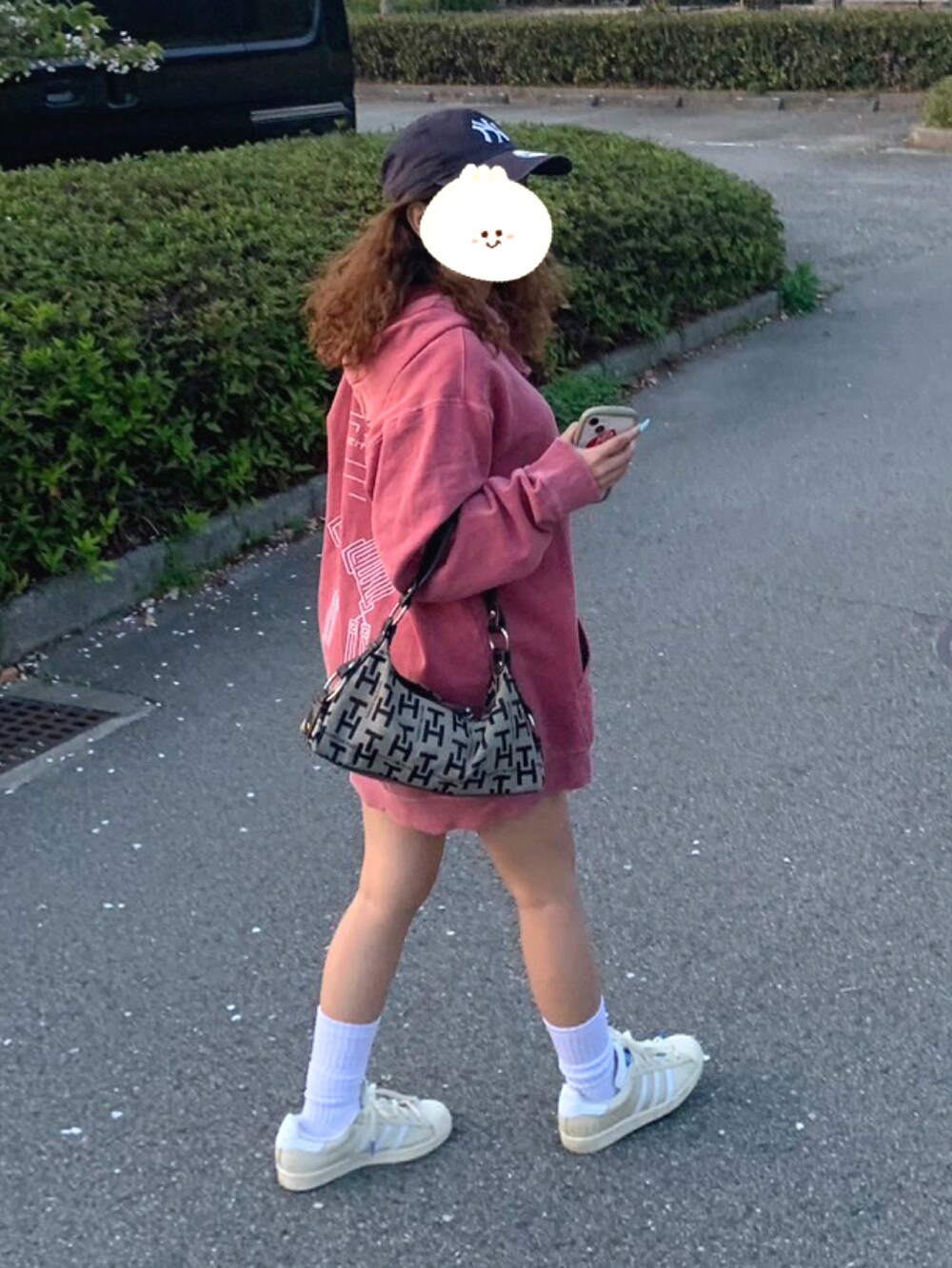 レッド系のパーカー、ベージュ系のバッグ、ホワイト系のスニーカーを着用したレディースの春コーディネートの3枚目の写真