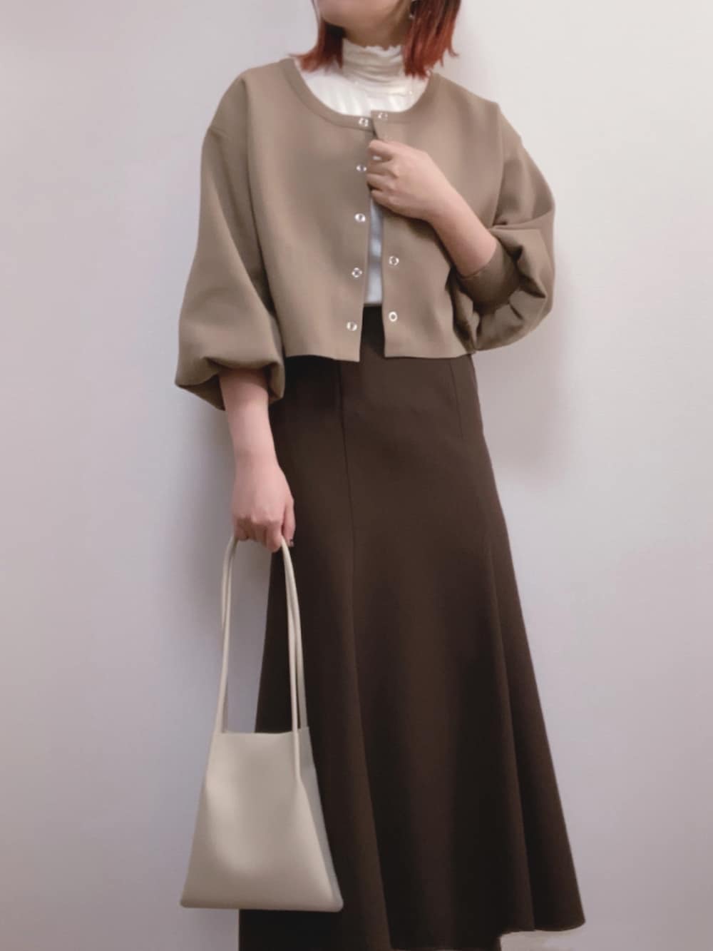 ブラウン系のカーディガン/ボレロ、ブラウン系のスカート、ホワイト系のトートバッグを着用したレディースの秋コーディネートの2枚目の写真