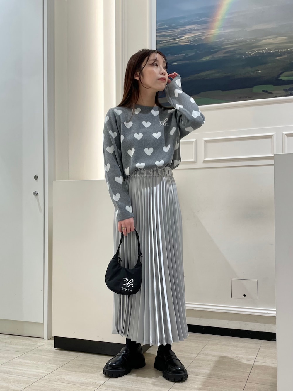 シルバー系のスカート、グレー系のニット/セーター、ブラック系のハンドバッグを着用したレディースの冬コーディネートの2枚目の写真