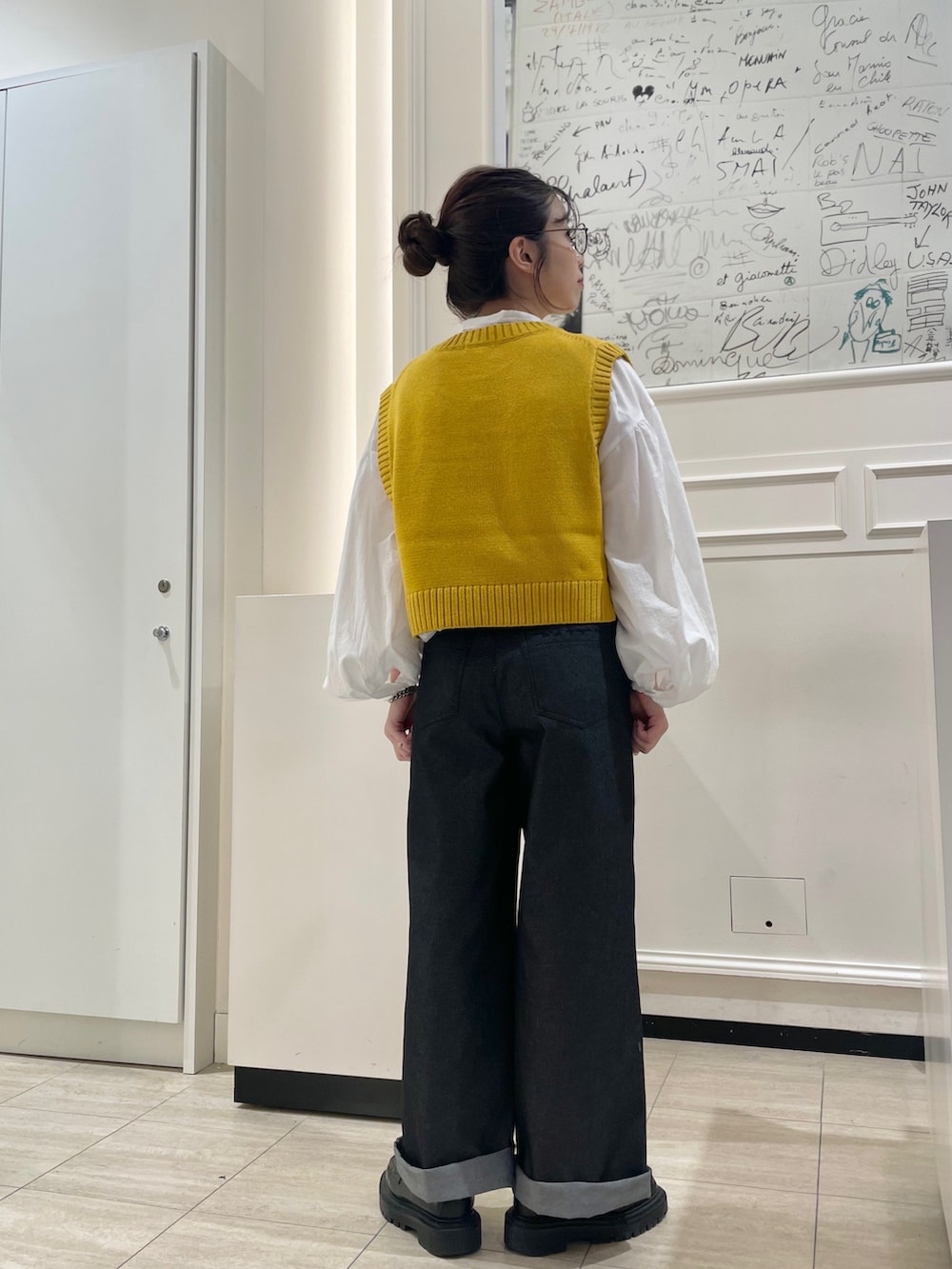 ホワイト系のシャツ/ブラウス、イエロー系のベスト、ブラック系のその他パンツを着用したレディースの秋コーディネートの3枚目の写真