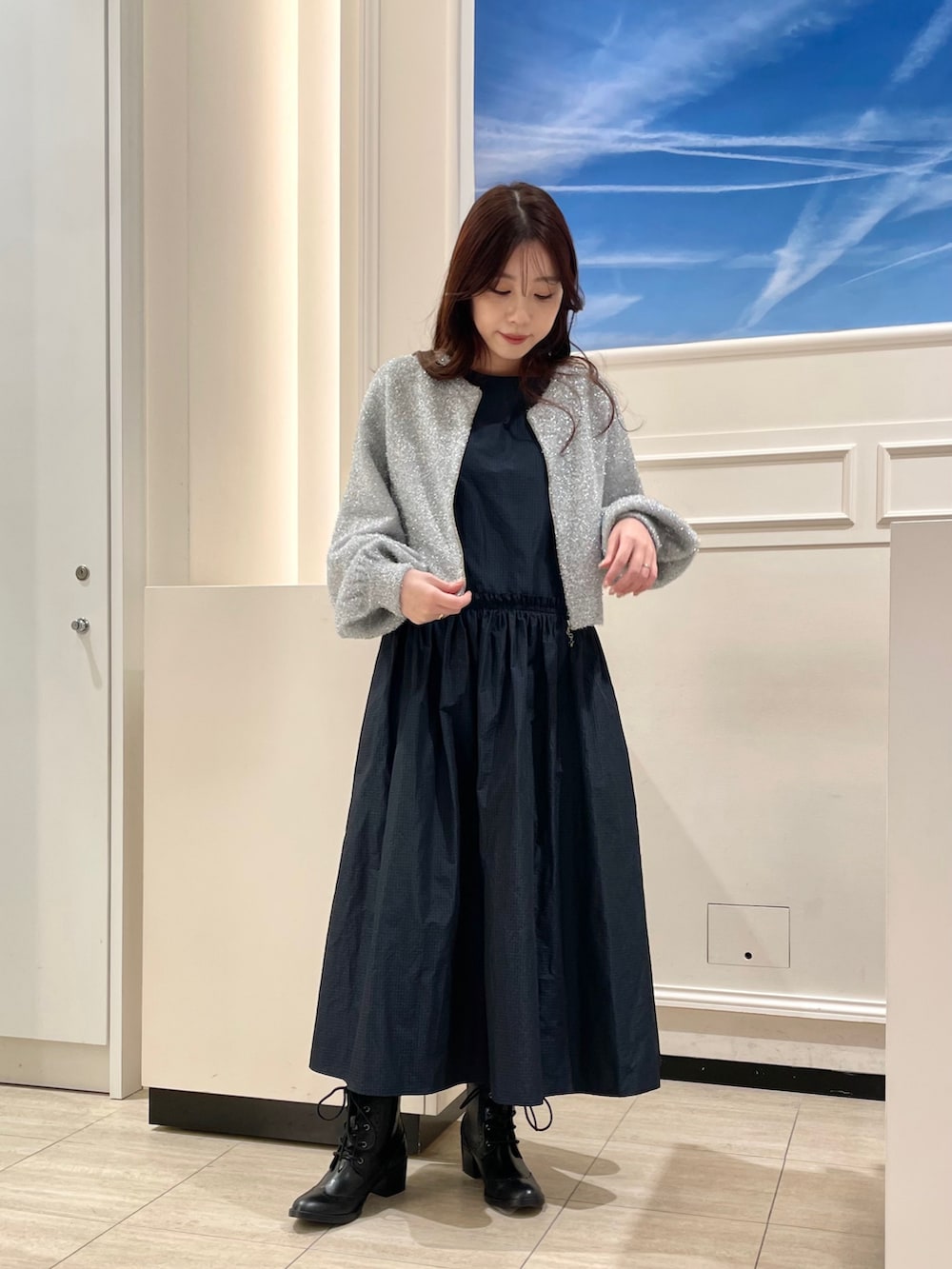 ブラック系のドレス、シルバー系のカーディガン/ボレロ、ブラック系のブーツを着用したレディースの冬コーディネートの2枚目の写真