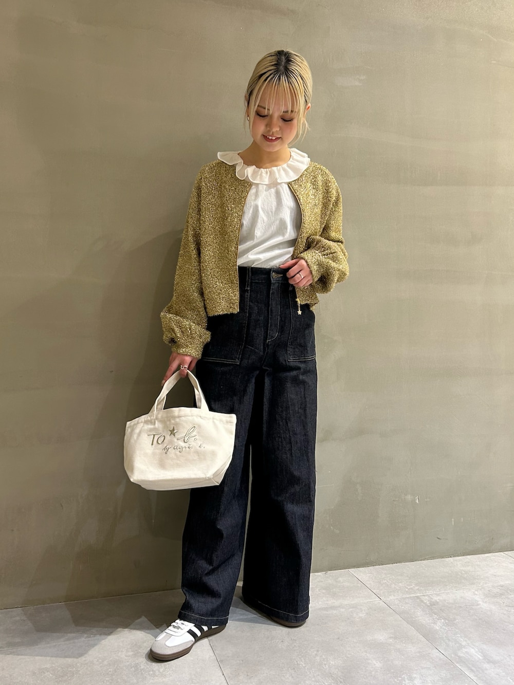 ゴールド系のカーディガン/ボレロ、ブルー系のデニムパンツ、ホワイト系のトートバッグを着用したレディースの春コーディネートの2枚目の写真