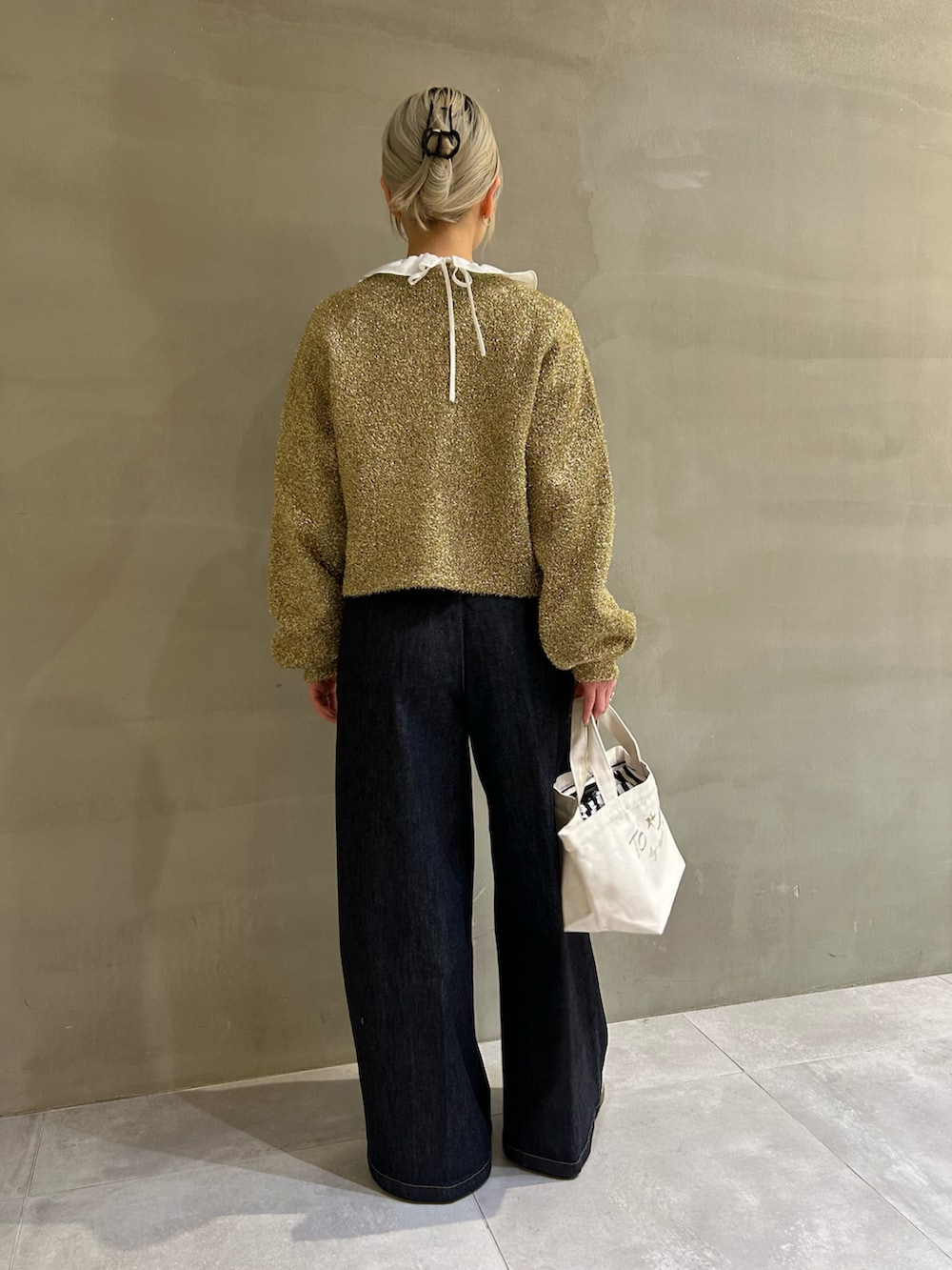 ゴールド系のカーディガン/ボレロ、ブルー系のデニムパンツ、ホワイト系のトートバッグを着用したレディースの春コーディネートの3枚目の写真