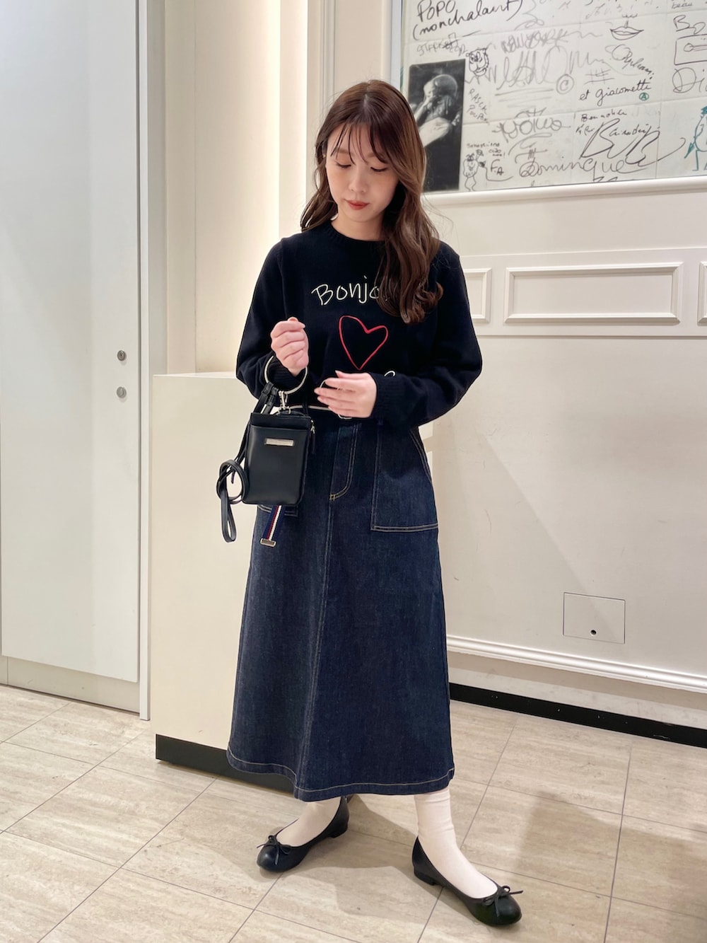 ブラック系のスウェット、ブルー系のスカート、ブラック系のショルダーバッグを着用したレディースの春コーディネートの2枚目の写真