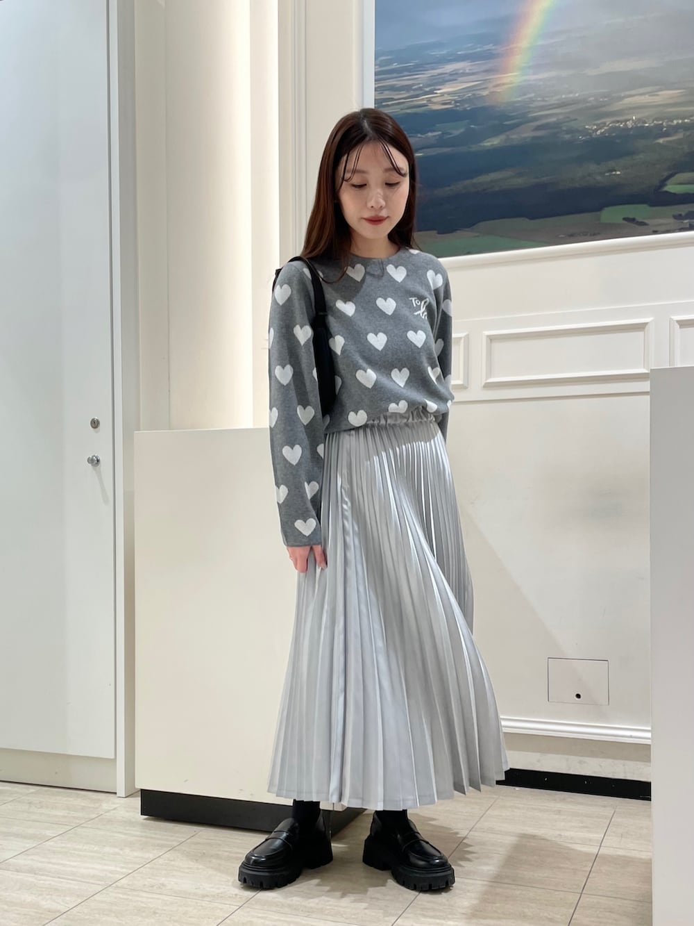 シルバー系のスカート、グレー系のニット/セーター、ブラック系のハンドバッグを着用したレディースの冬コーディネートの3枚目の写真