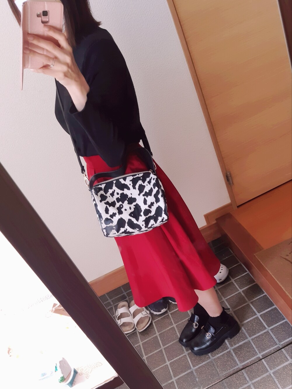 レッド系のスカート、ブラック系のローファー、ホワイト系のショルダーバッグを着用したレディースの春コーディネートの2枚目の写真
