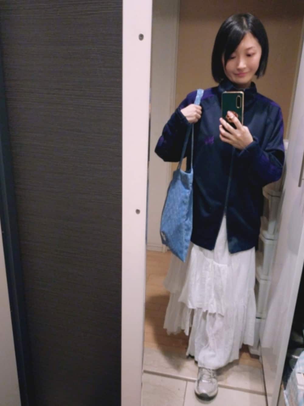 ブルー系のトートバッグ、ホワイト系のスカート、ブラック系のジャケット/アウターを着用したレディースの冬コーディネートの3枚目の写真