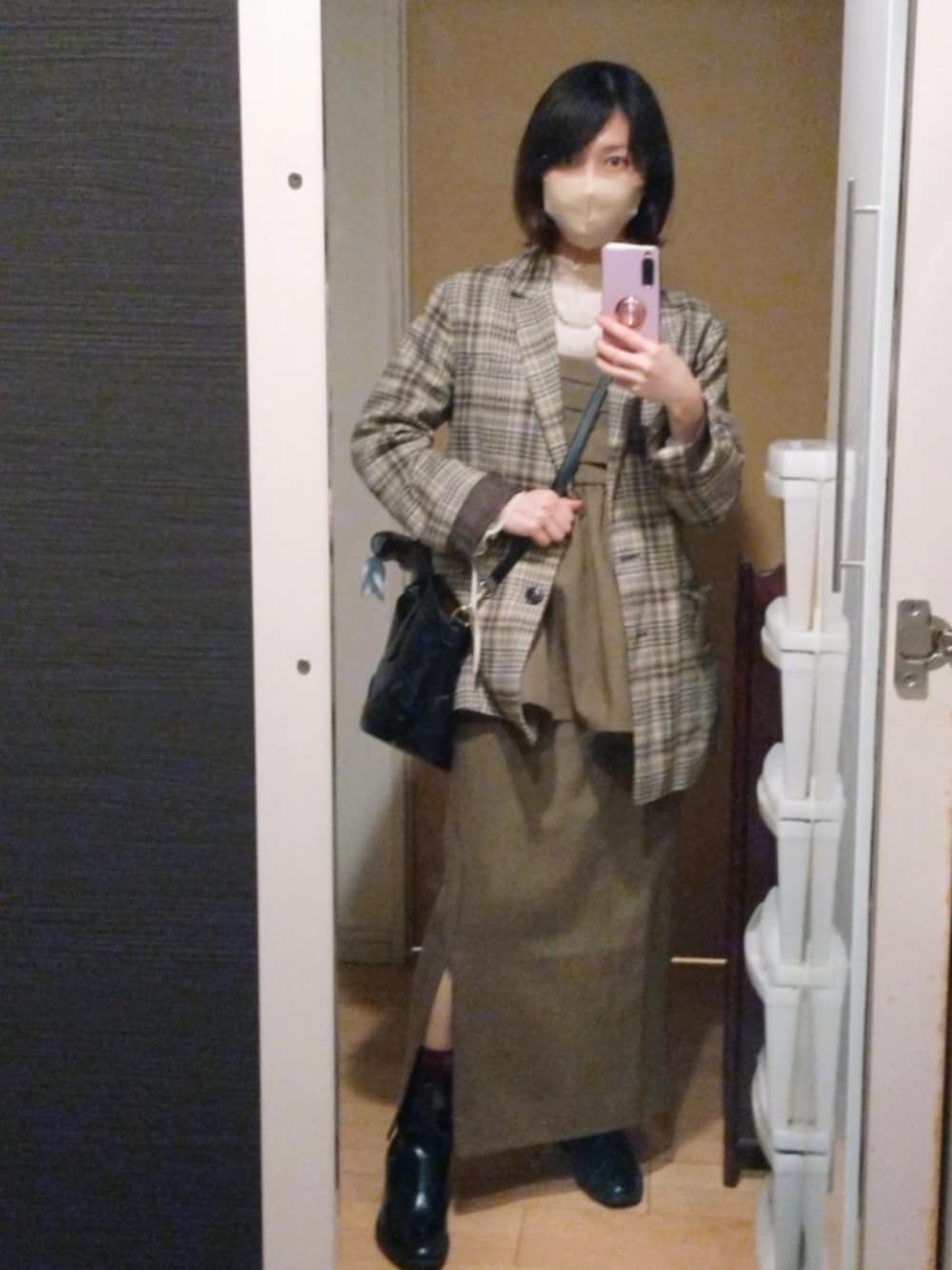 ベージュ系のテーラードジャケット、ブラウン系のワンピース、ブラック系のブーツを着用したレディースの春コーディネートの2枚目の写真