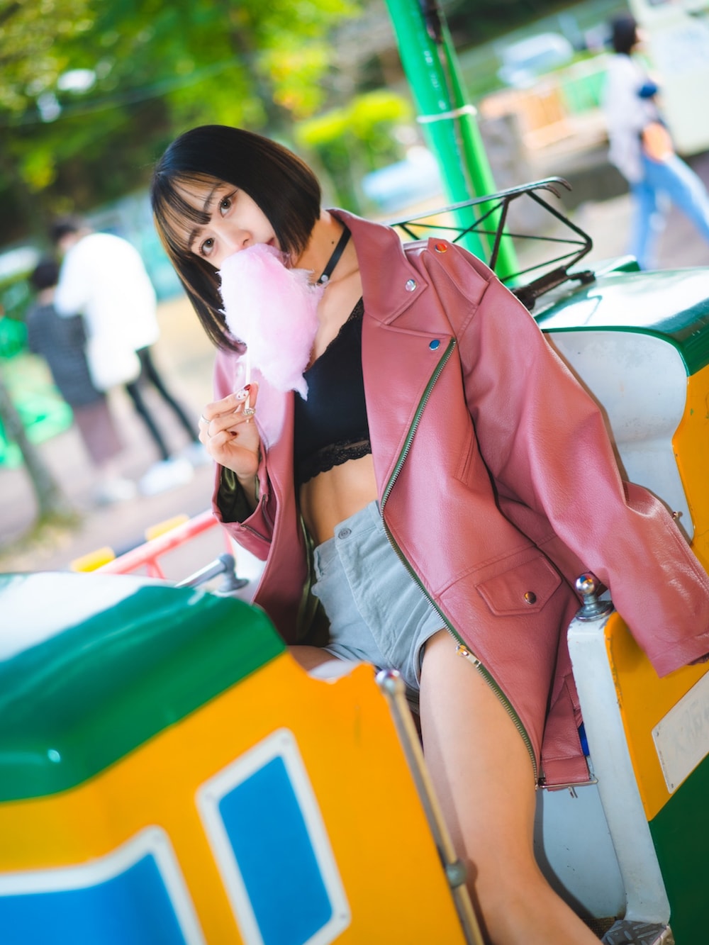 ピンク系のライダースジャケット、グレー系のパンツ、ブラック系のチョーカーを着用したレディースの秋コーディネートの2枚目の写真