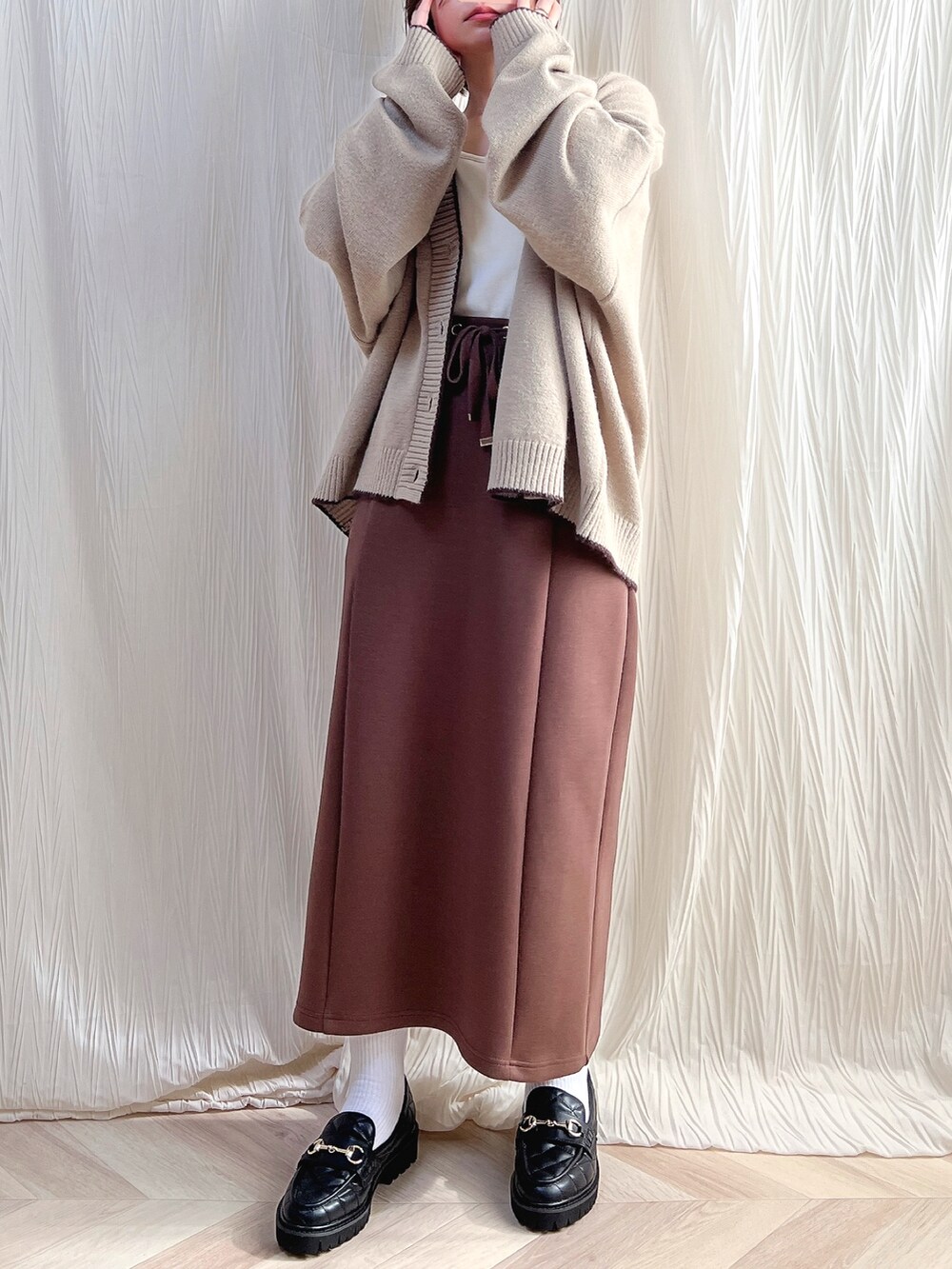 ベージュ系のカーディガン/ボレロ、ブラウン系のスカート、ブラック系のローファーを着用したレディースの秋コーディネートの2枚目の写真