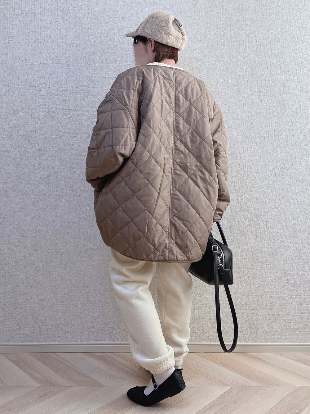 ホワイト系のノーカラーコート、ホワイト系のニット/セーター、ブラック系のボストンバッグを着用したレディースの冬コーディネートの2枚目の写真