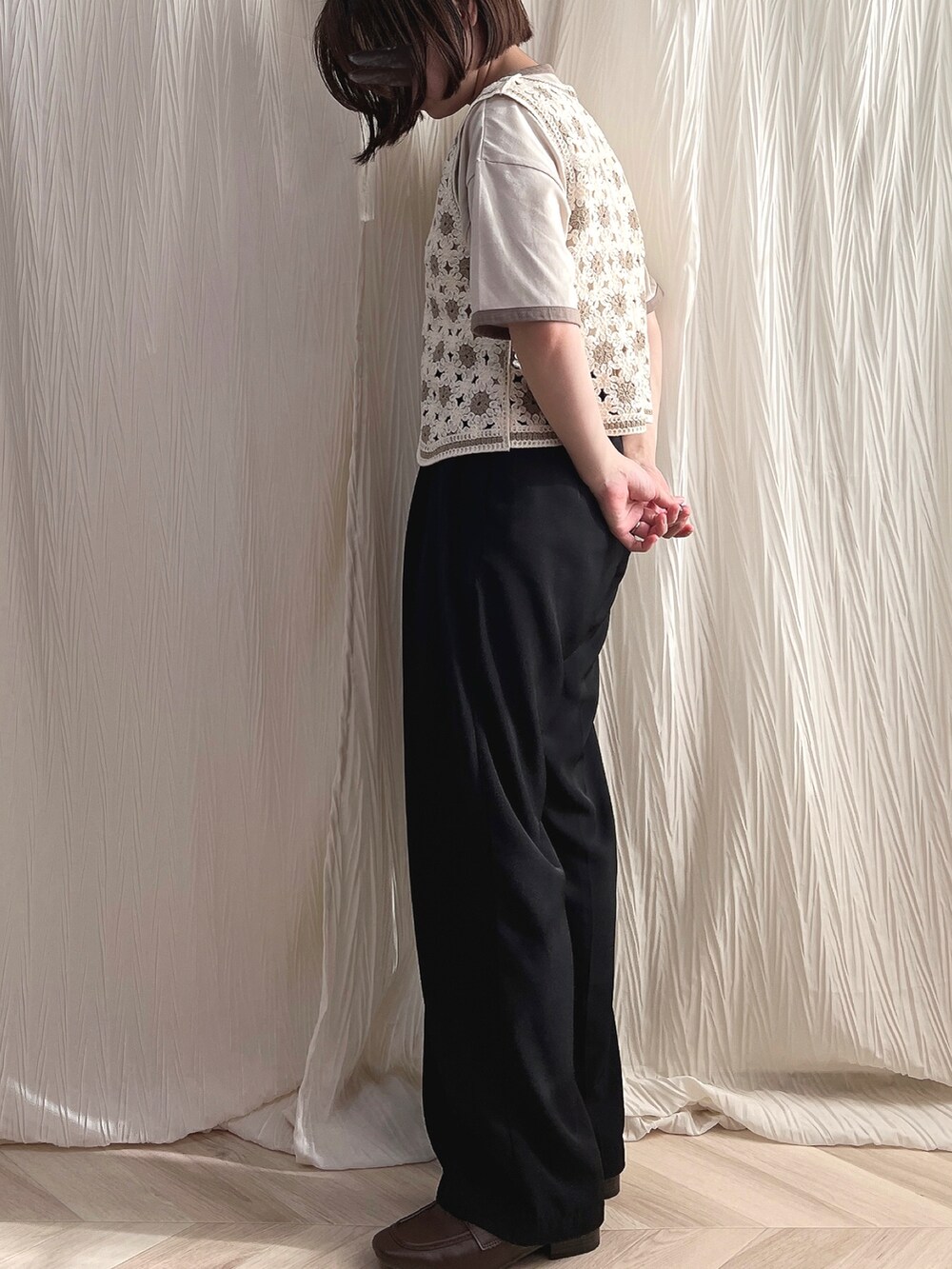 ブラック系のスラックス、ベージュ系のベスト、ブラウン系のローファーを着用したレディースの秋コーディネートの2枚目の写真