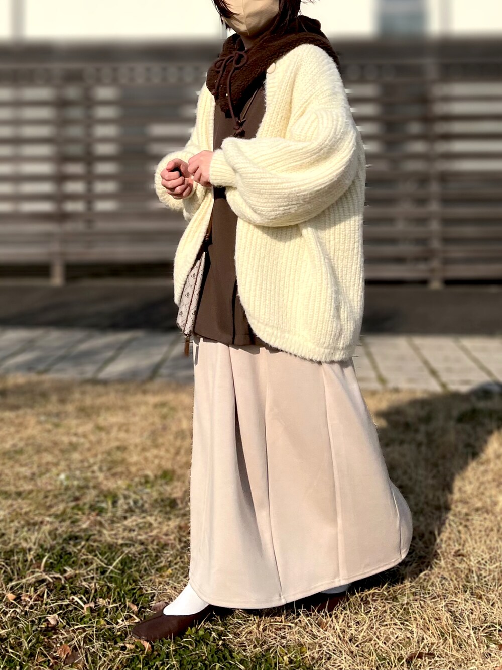 ベージュ系のワンピース、ホワイト系のカーディガン/ボレロ、その他のショルダーバッグを着用したレディースの冬コーディネートの2枚目の写真