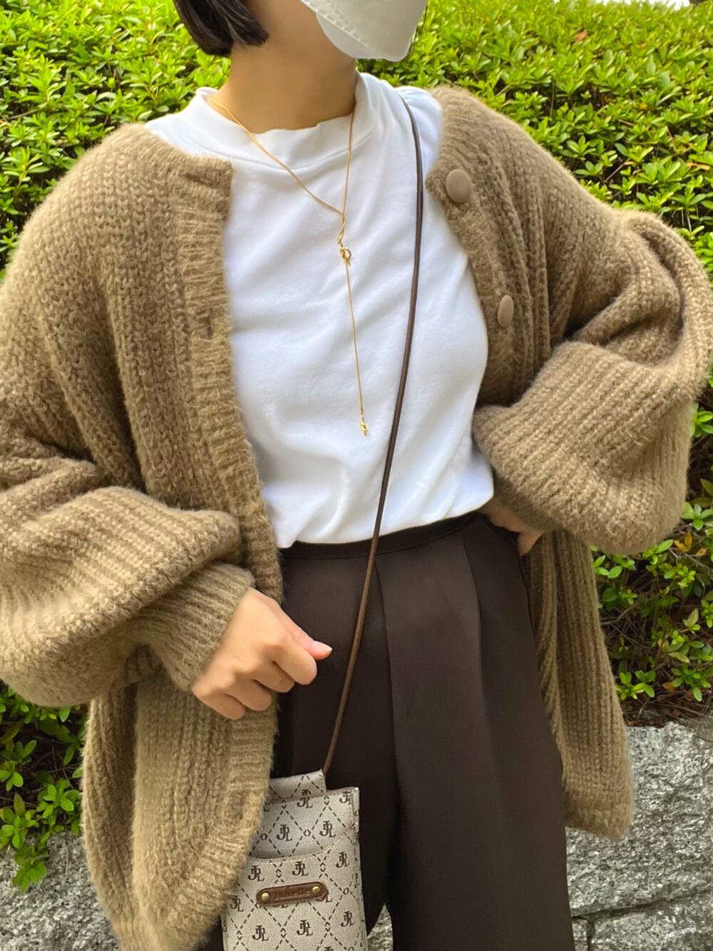 ホワイト系のカーディガン/ボレロ、ブラウン系のスラックス、その他のショルダーバッグを着用したレディースの秋コーディネートの2枚目の写真