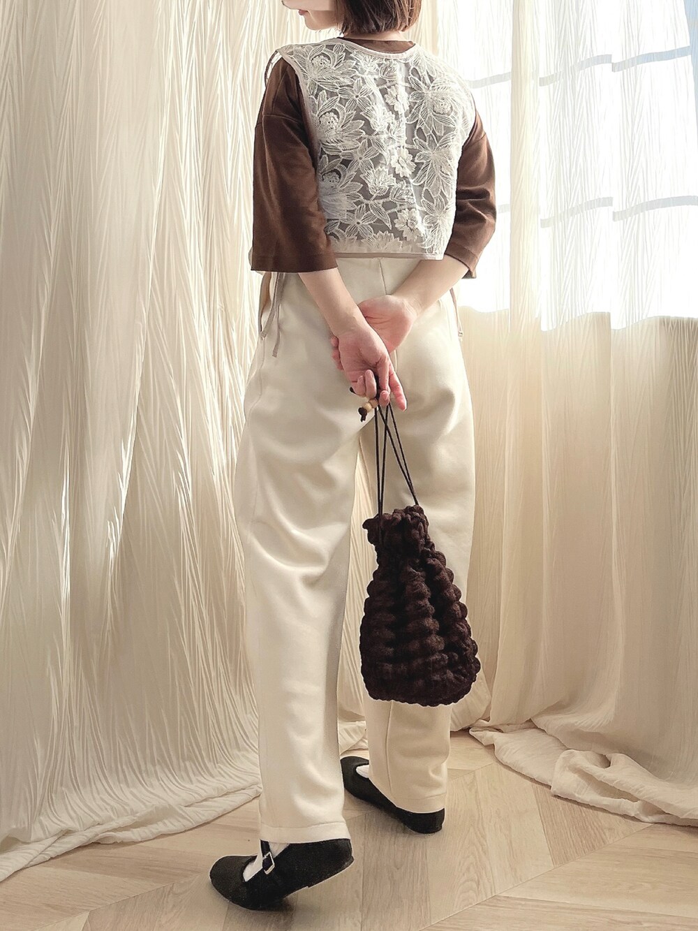 ベージュ系のベスト、ホワイト系のスウェットパンツ、ブラウン系のバッグを着用したレディースの秋コーディネートの2枚目の写真