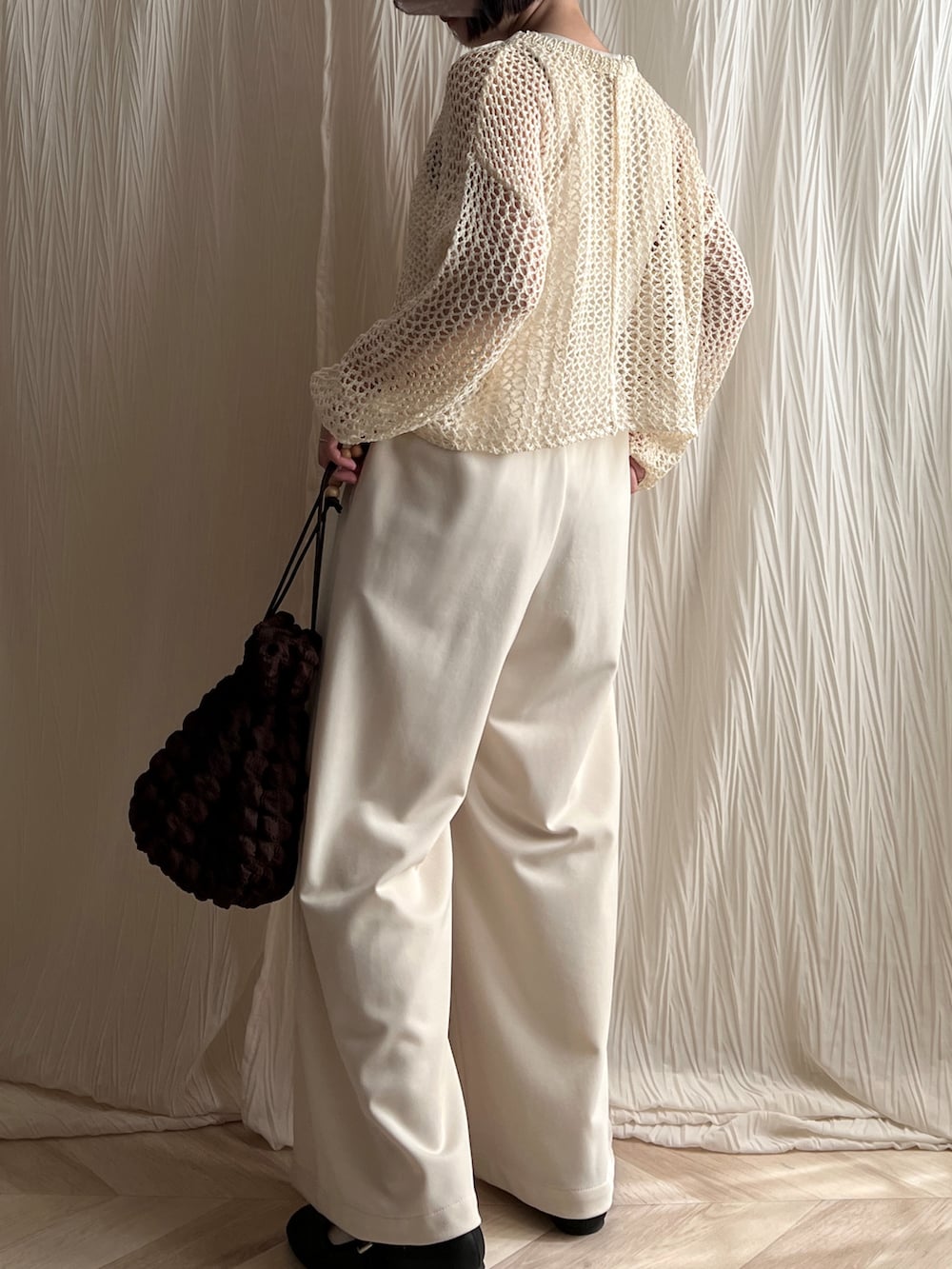 ホワイト系のニット/セーター、ホワイト系のサロペット/オーバーオール、ブラウン系のバッグを着用したレディースの春コーディネートの2枚目の写真