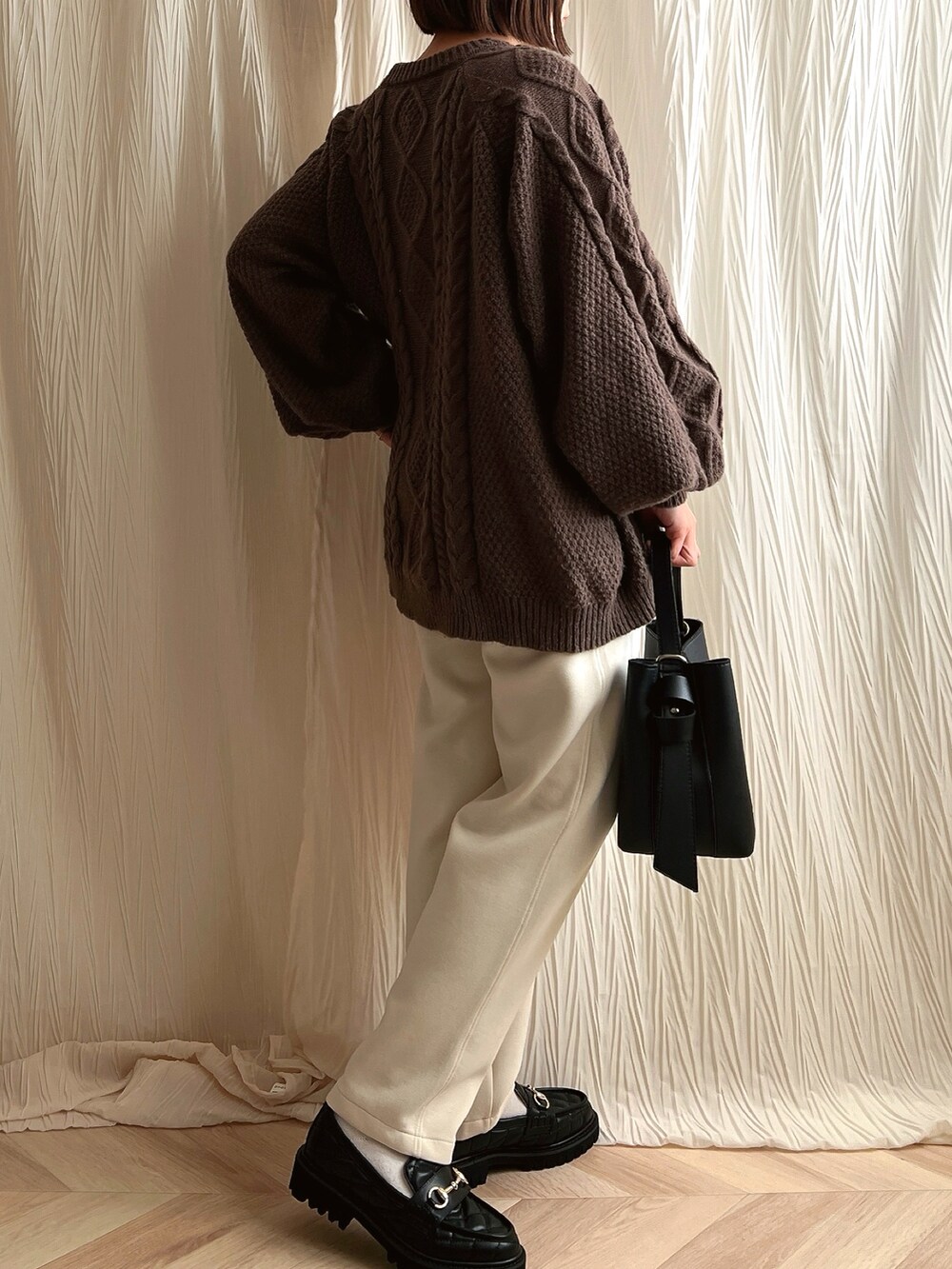 ブラウン系のニット/セーター、ホワイト系のスウェットパンツ、ブラック系のローファーを着用したレディースの冬コーディネートの2枚目の写真