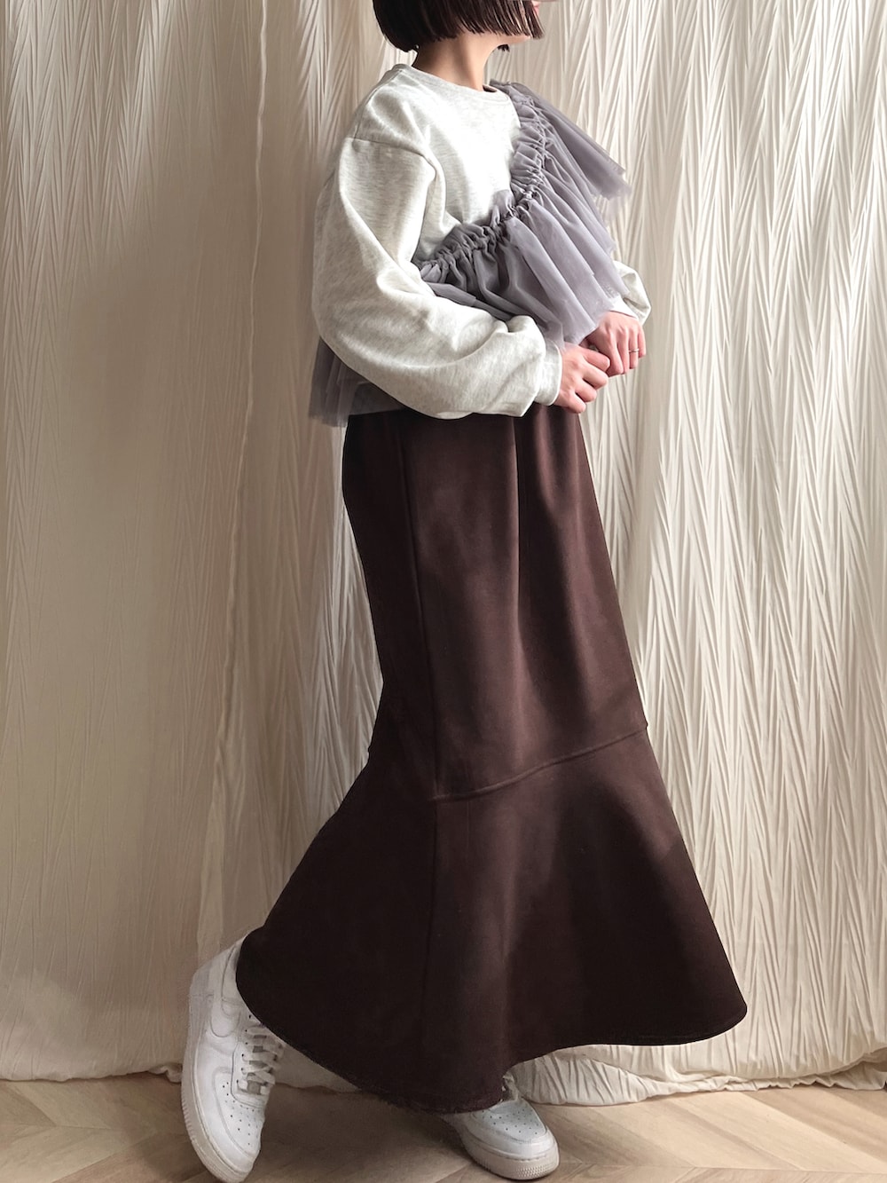 ブラウン系のジャンパースカート、ホワイト系のスニーカー、グレー系の付け襟を着用したレディースの春コーディネートの2枚目の写真