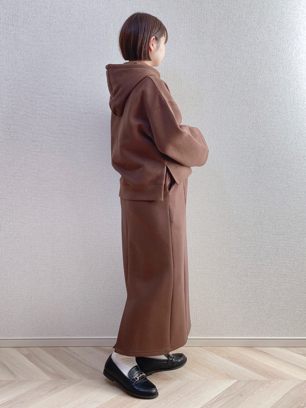 ブラウン系のパーカー、ブラウン系のスカート、ブラック系のローファーを着用したレディースの冬コーディネートの2枚目の写真