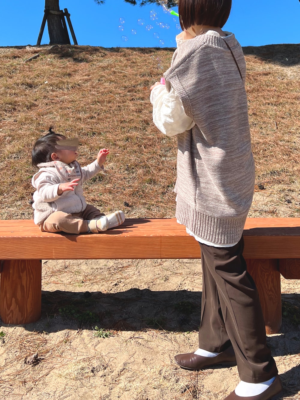 ホワイト系のTシャツ/カットソー、ベージュ系のベスト、ブラウン系のスラックスを着用したレディースの冬コーディネートの2枚目の写真