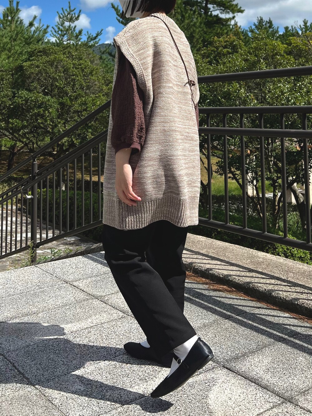 ベージュ系のベスト、その他のショルダーバッグ、ブラック系のスラックスを着用したレディースの秋コーディネートの2枚目の写真