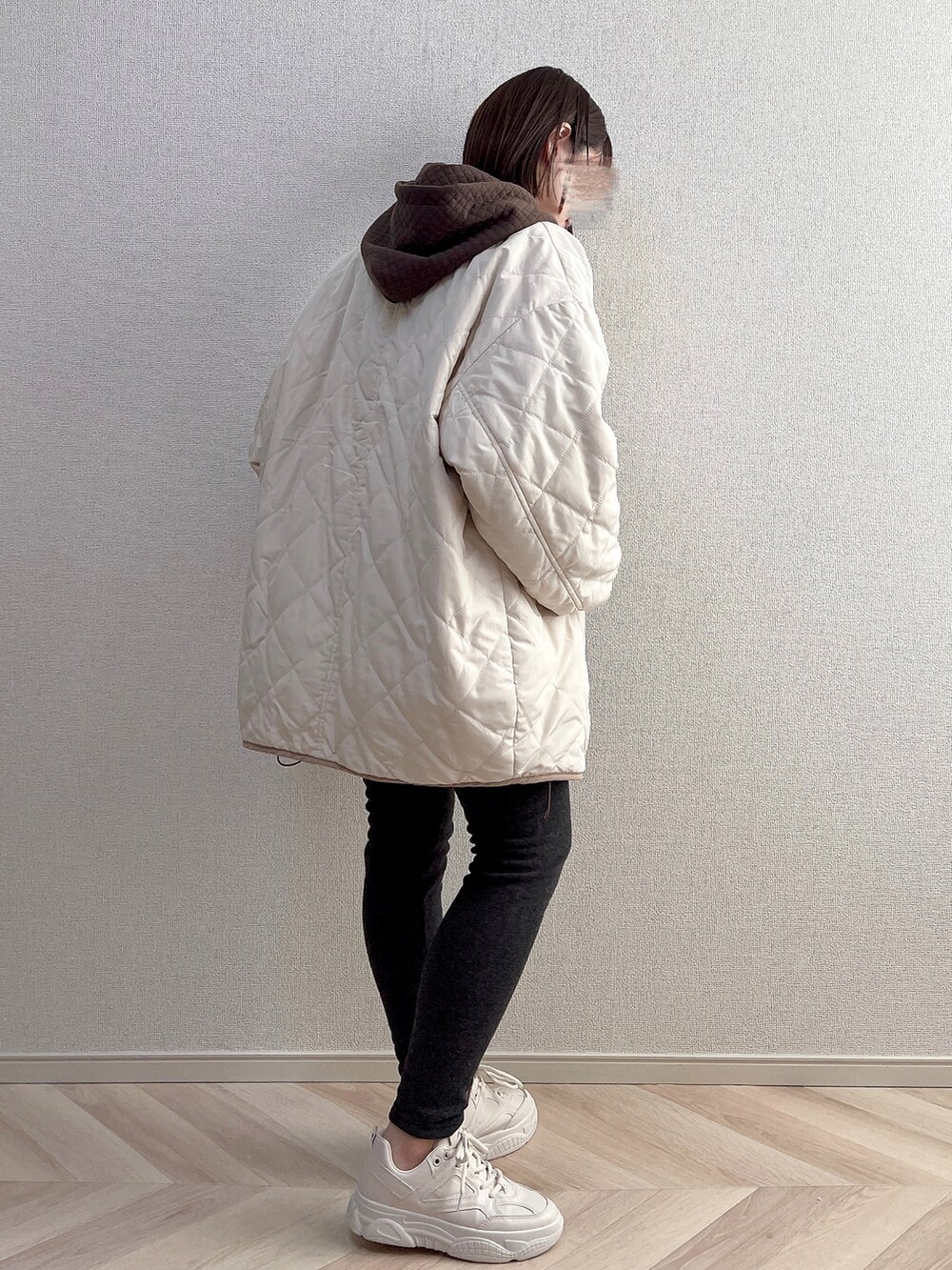 ホワイト系のダウンジャケット/コート、ブラウン系のパーカー、ベージュ系のスニーカーを着用したレディースの秋コーディネートの2枚目の写真