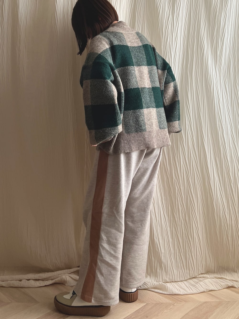 グリーン系のニット/セーター、ベージュ系のパンツ、ブラウン系のスニーカーを着用したレディースの冬コーディネートの2枚目の写真