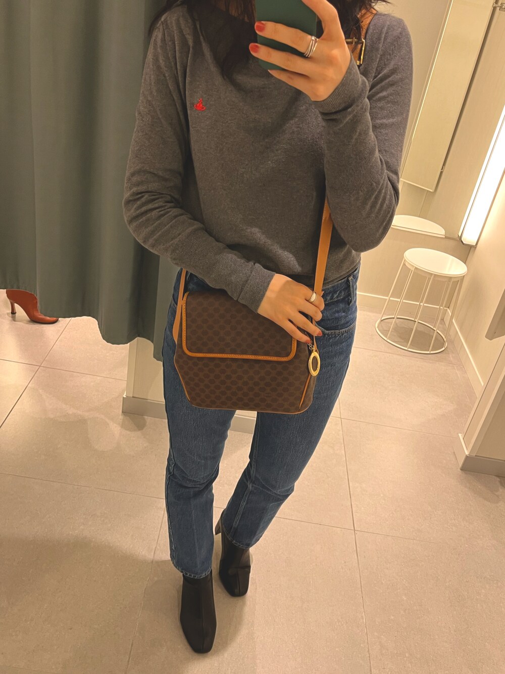 ブラック系のブーツ、ブルー系のデニムパンツ、ブラウン系のショルダーバッグを着用したレディースの春コーディネートの2枚目の写真