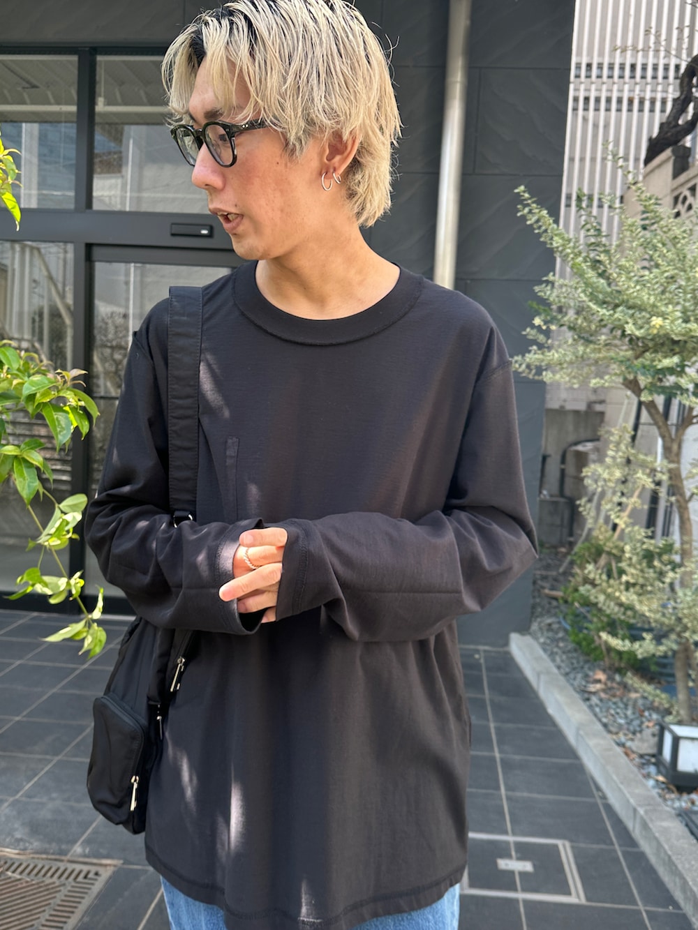 ブラック系のTシャツ/カットソー、ブルー系のデニムパンツ、ブラック系のショルダーバッグを着用したメンズの春コーディネートの3枚目の写真
