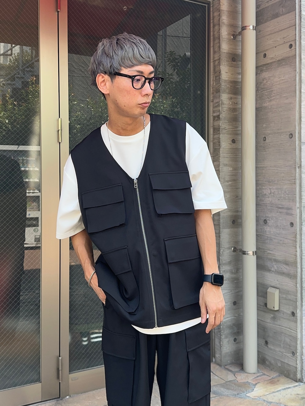 ホワイト系のTシャツ/カットソー、ブラック系のベスト、ブラック系のカーゴパンツを着用したメンズの夏コーディネートの4枚目の写真