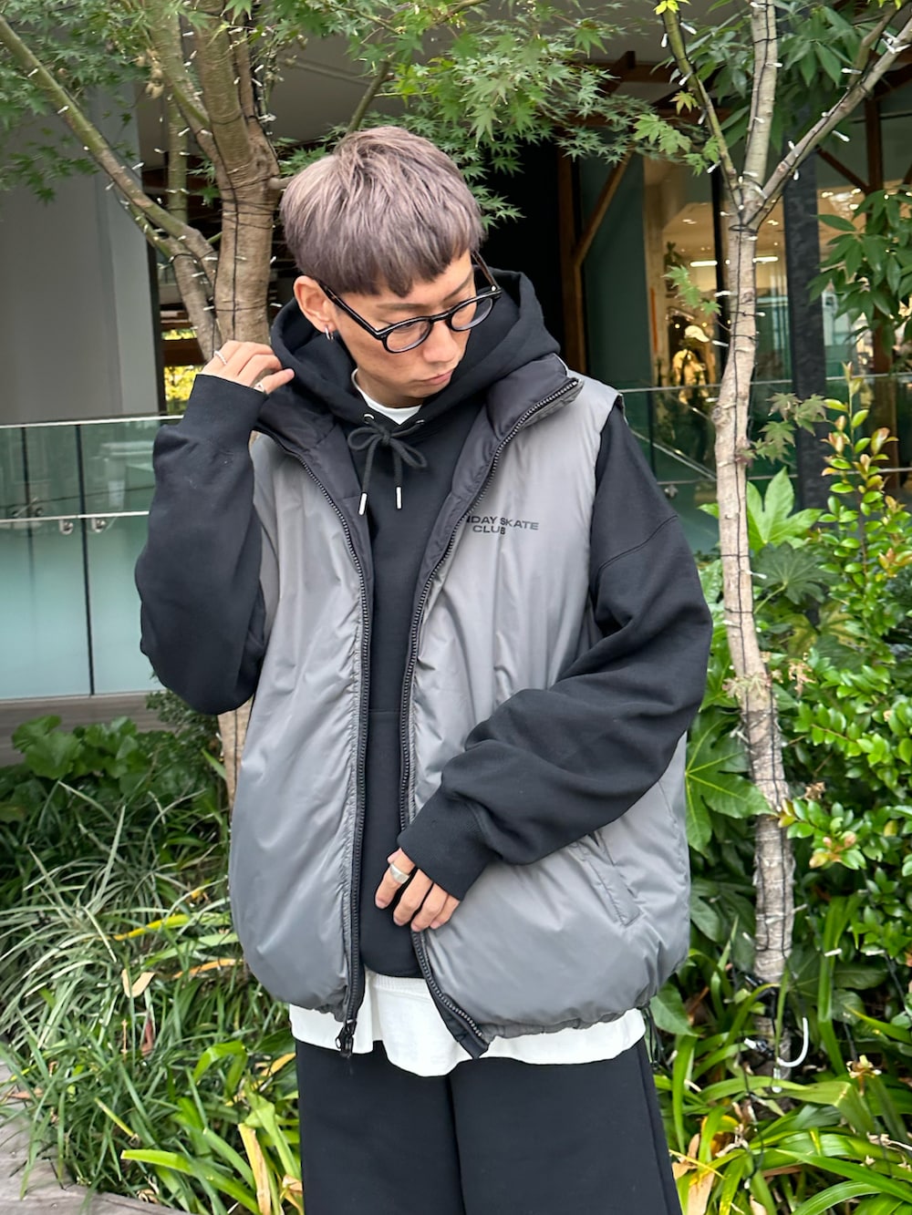 ブラック系のダウンベスト、ブラック系のパーカー、ホワイト系のスニーカーを着用したメンズの秋コーディネートの2枚目の写真