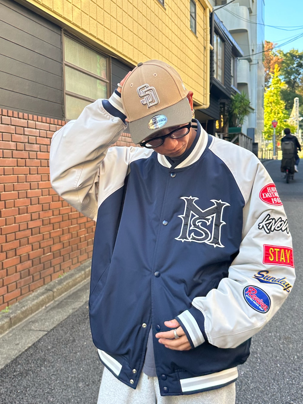 ブルー系のスタジャン、ブラック系のTシャツ/カットソー、ホワイト系のスニーカーを着用したメンズの秋コーディネートの4枚目の写真