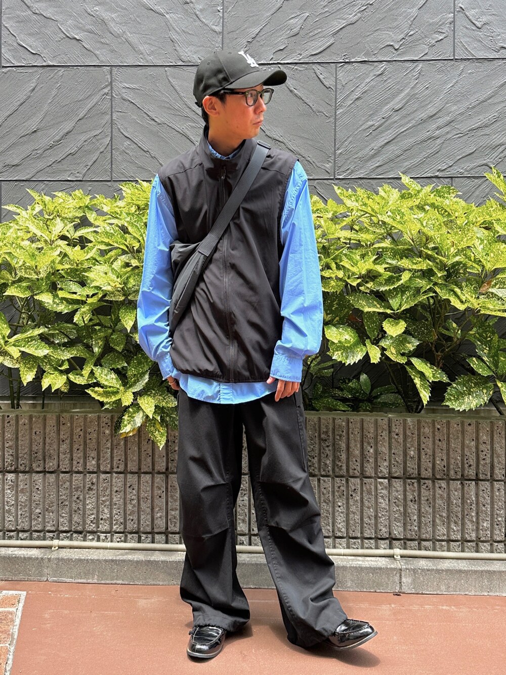 ブラック系のベスト、ブルー系のシャツ/ブラウス、ブラック系のカーゴパンツを着用したメンズの夏コーディネートの2枚目の写真