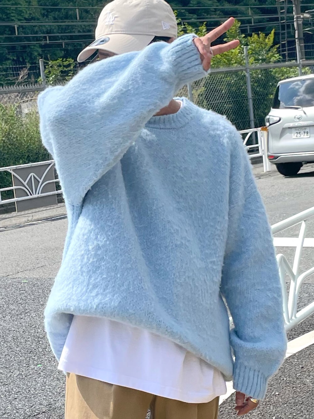 ベージュ系のチノパンツ、ホワイト系のスニーカー、ブルー系のニット/セーターを着用したメンズの夏コーディネートの2枚目の写真