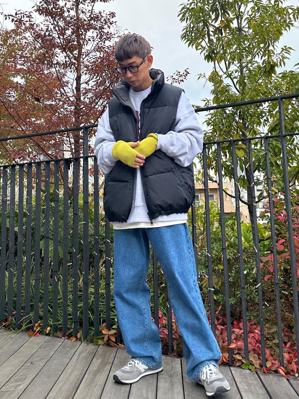 ブラック系のダウンベスト、ベージュ系のスウェット、ブルー系のデニムパンツを着用したメンズの秋コーディネートの3枚目の写真