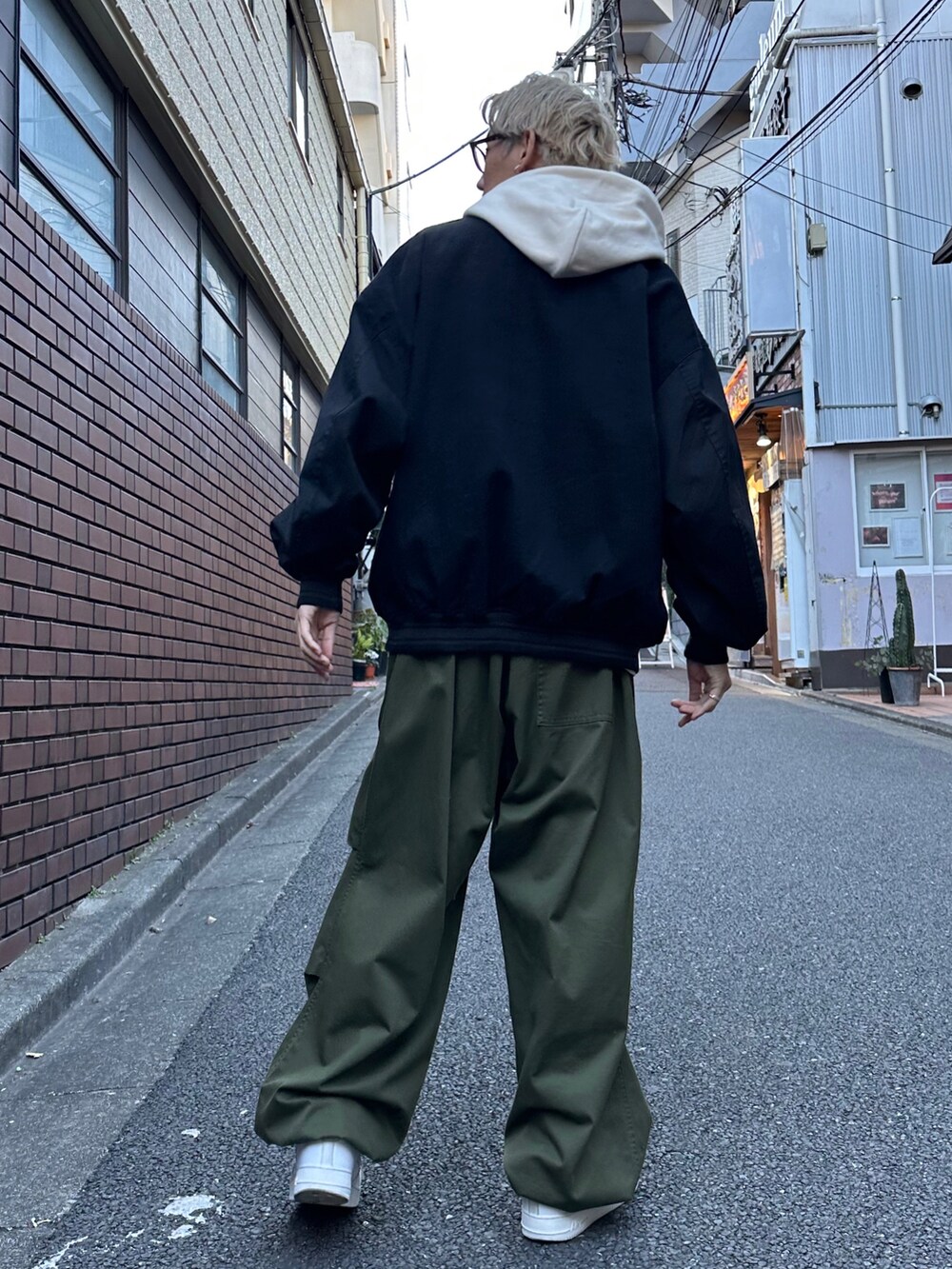 ブラック系のスタジャン、ベージュ系のパーカー、グリーン系のカーゴパンツを着用したメンズの冬コーディネートの2枚目の写真