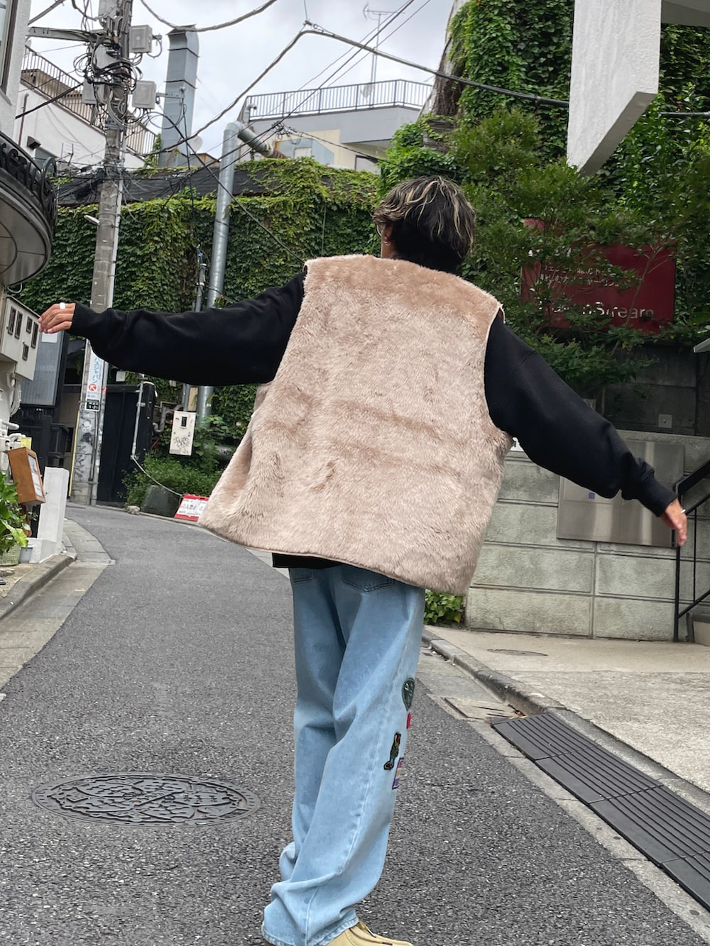 グレー系のベスト、ブラック系のスウェット、ブルー系のデニムパンツを着用したメンズの夏コーディネートの2枚目の写真