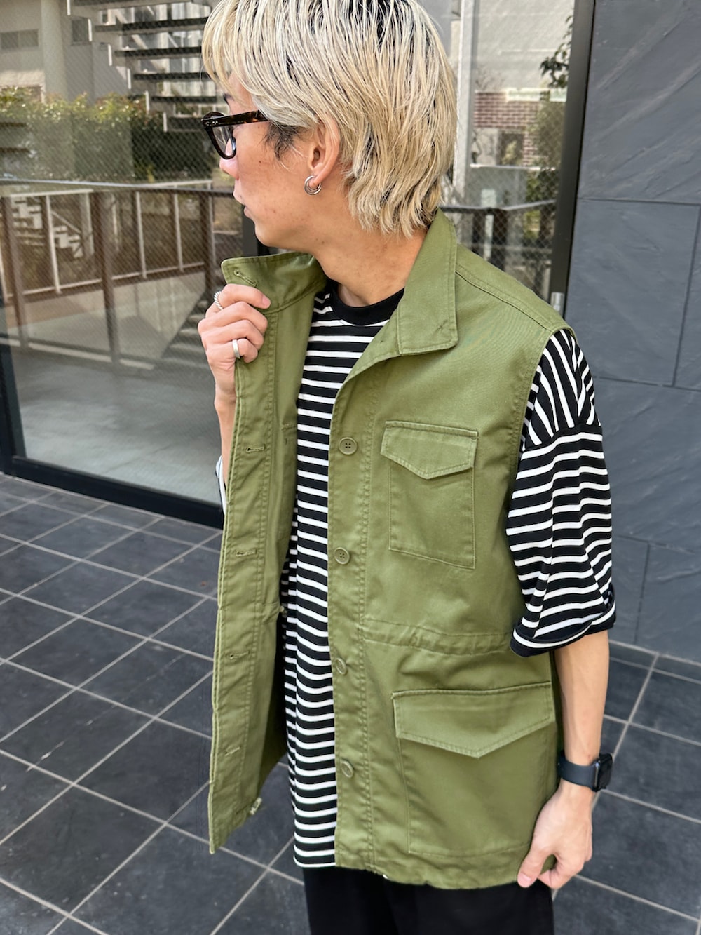 グリーン系のベスト、ブラック系のTシャツ/カットソー、ブラック系のチノパンツを着用したメンズの春コーディネートの5枚目の写真