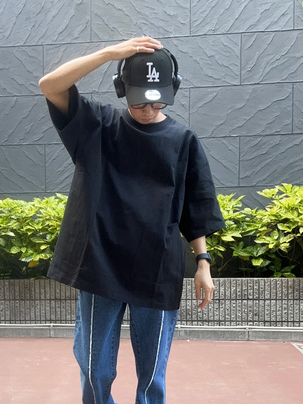 ブラック系のTシャツ/カットソー、ブラック系のスニーカー、ブルー系のデニムパンツを着用したメンズの夏コーディネートの4枚目の写真
