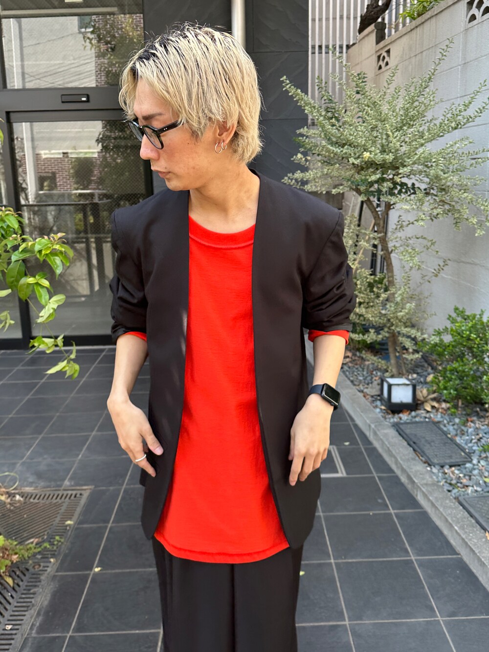 ブラック系のテーラードジャケット、オレンジ系のTシャツ/カットソー、ブラック系のスラックスを着用したメンズの春コーディネートの4枚目の写真
