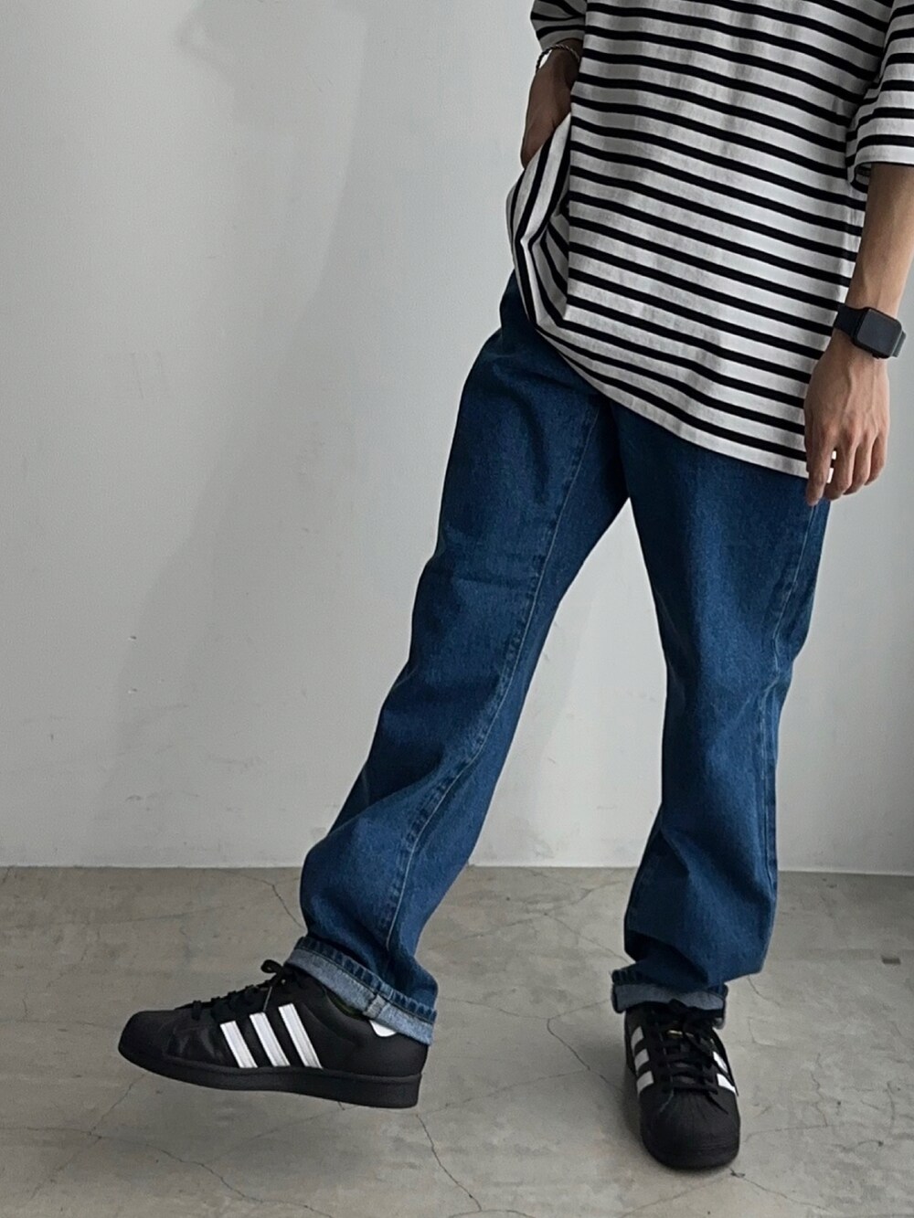 ホワイト系のTシャツ/カットソー、ブルー系のデニムパンツ、ブラック系のスニーカーを着用したメンズの春コーディネートの4枚目の写真