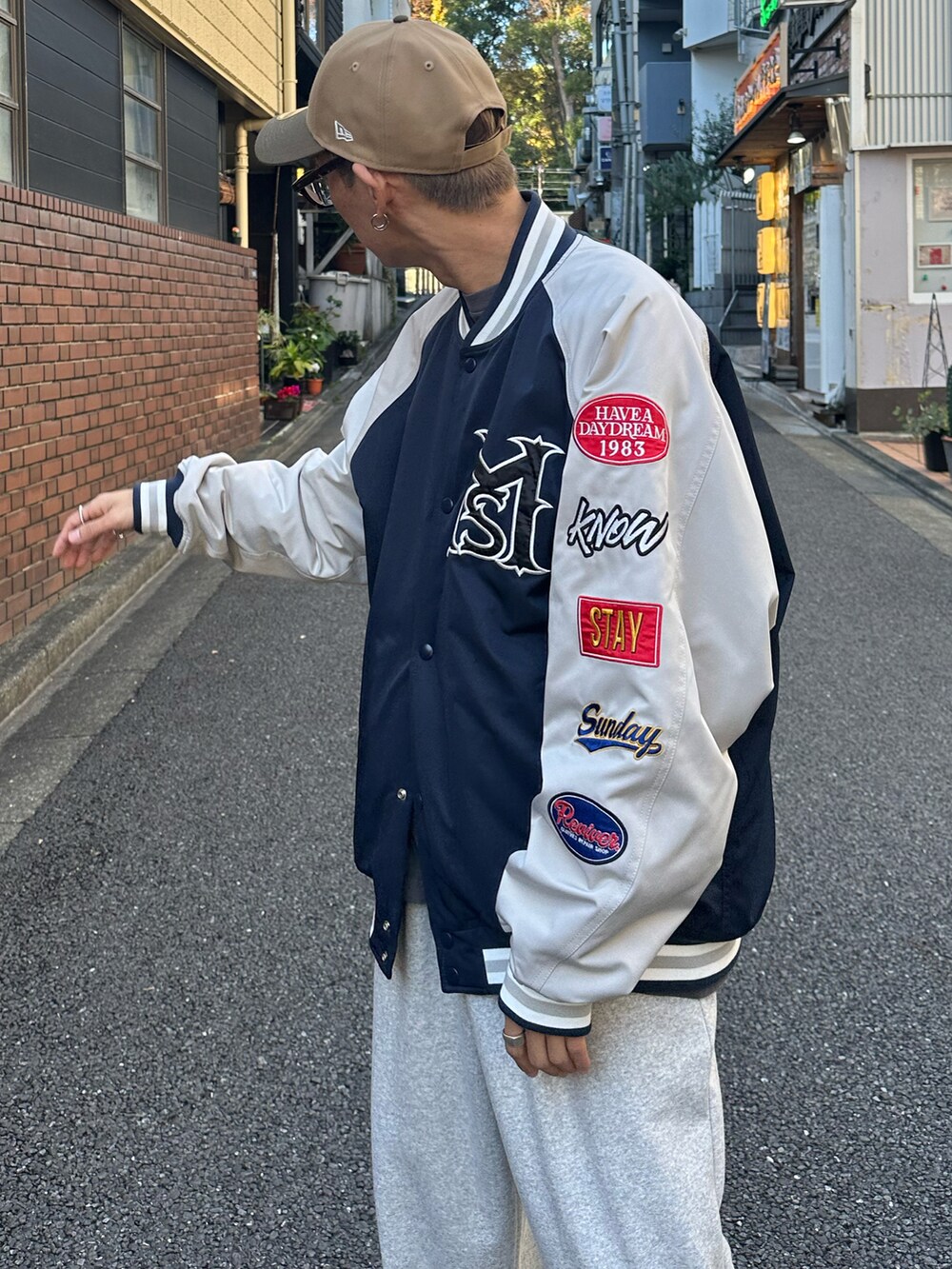 ブルー系のスタジャン、ブラック系のTシャツ/カットソー、ホワイト系のスニーカーを着用したメンズの秋コーディネートの5枚目の写真