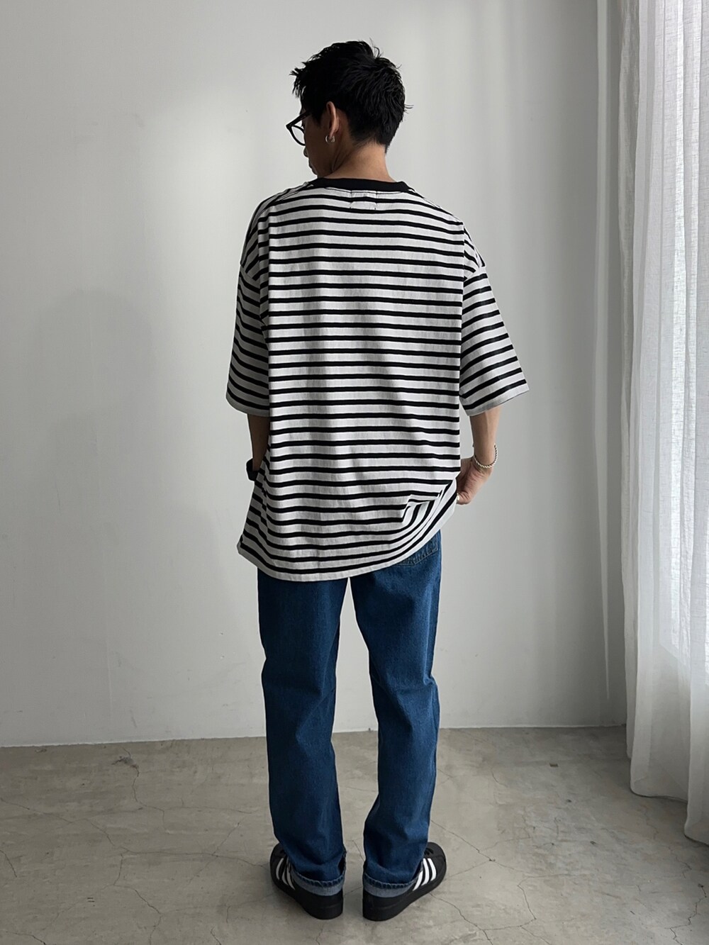 ホワイト系のTシャツ/カットソー、ブルー系のデニムパンツ、ブラック系のスニーカーを着用したメンズの春コーディネートの2枚目の写真