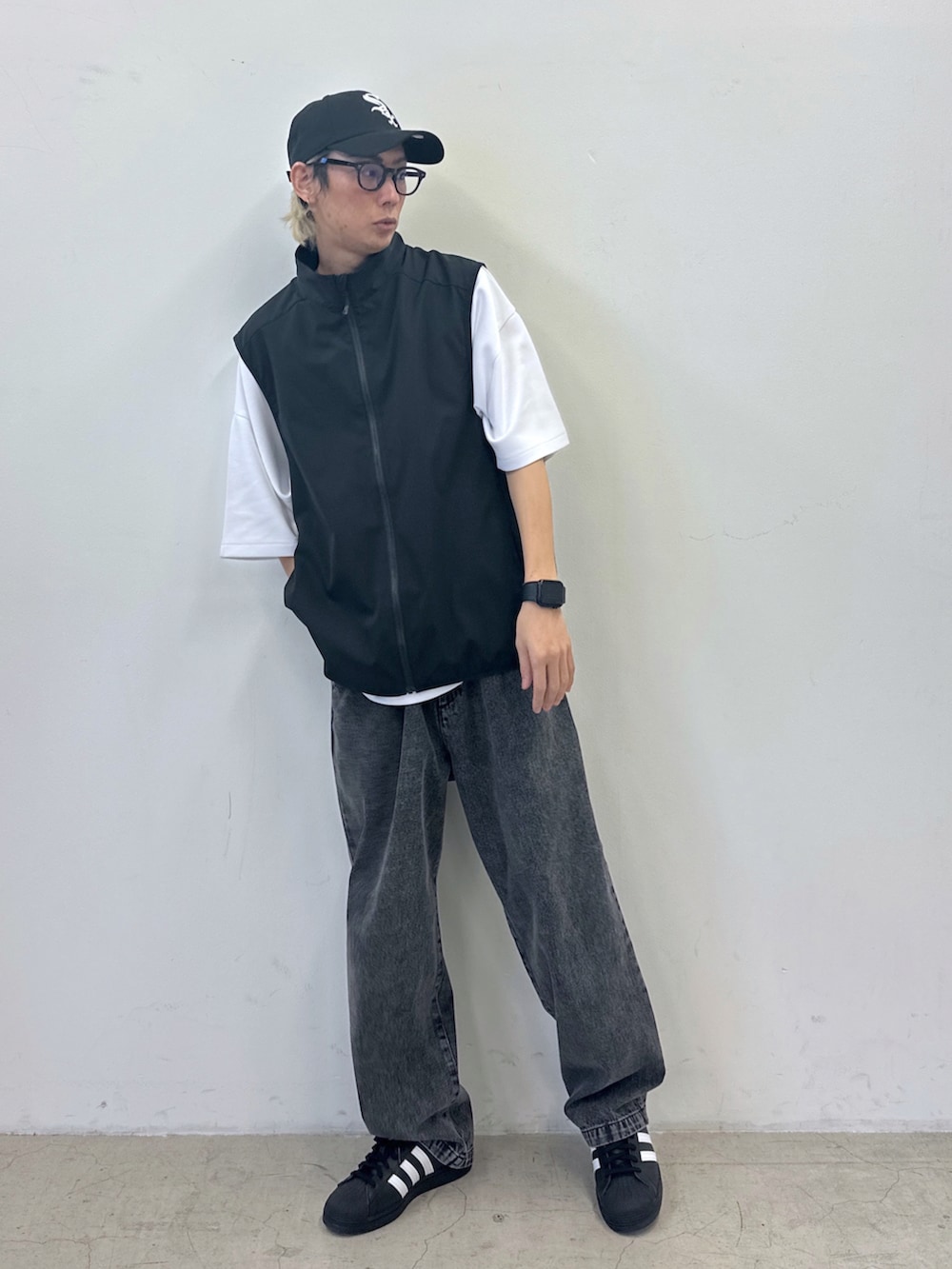 ホワイト系のTシャツ/カットソー、ブラック系のベスト、ブラック系のデニムパンツを着用したメンズの春コーディネートの2枚目の写真