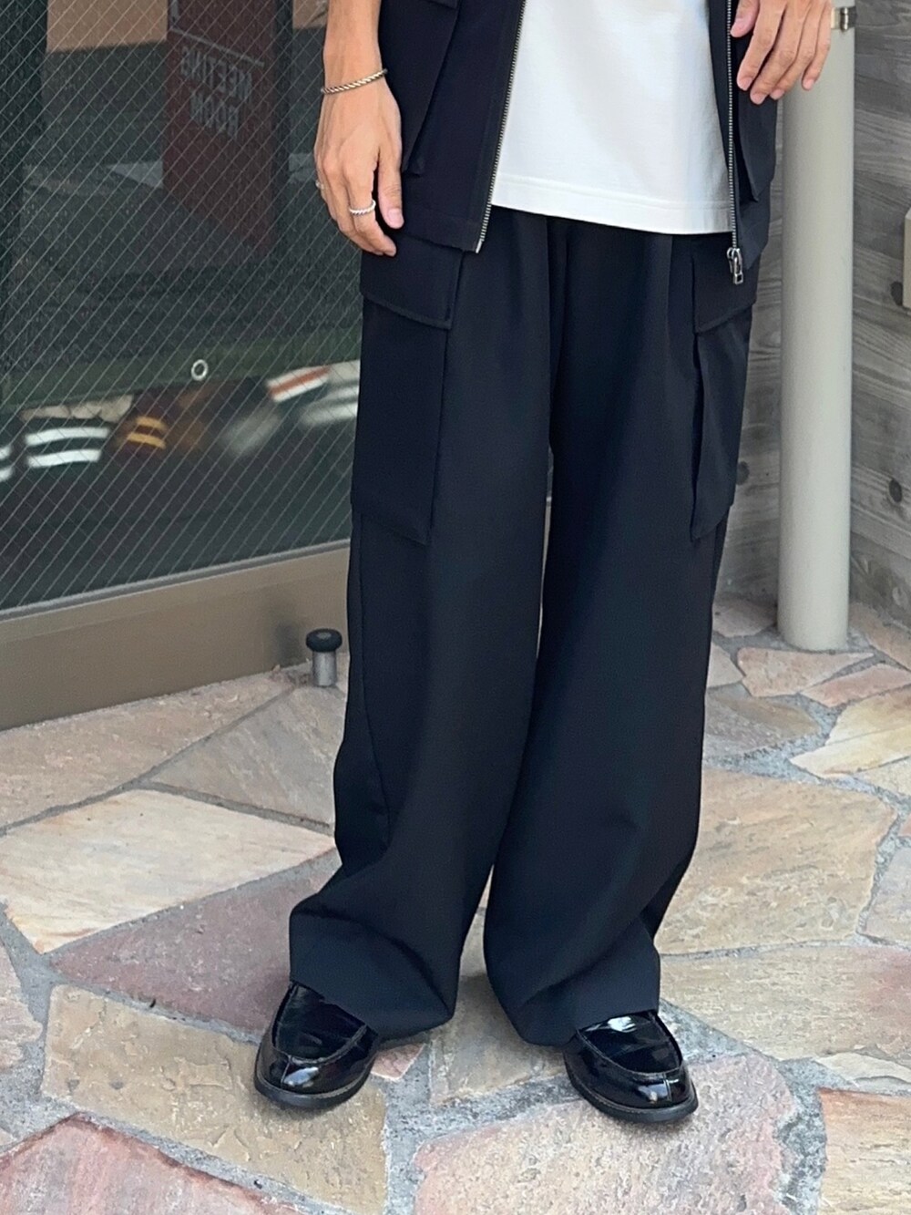 ホワイト系のTシャツ/カットソー、ブラック系のベスト、ブラック系のカーゴパンツを着用したメンズの夏コーディネートの5枚目の写真