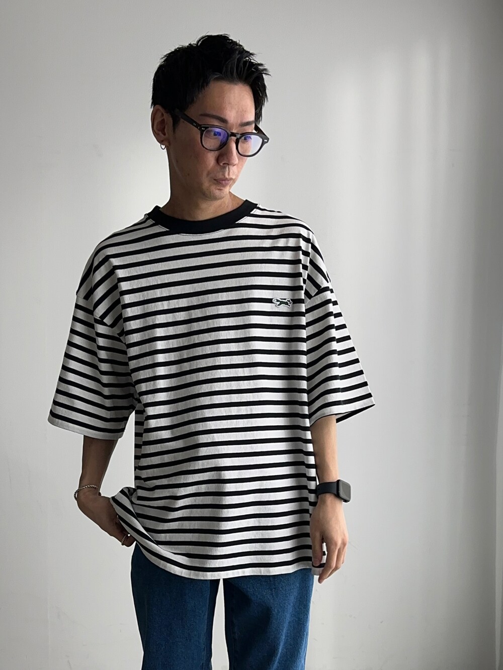 ホワイト系のTシャツ/カットソー、ブルー系のデニムパンツ、ブラック系のスニーカーを着用したメンズの春コーディネートの3枚目の写真