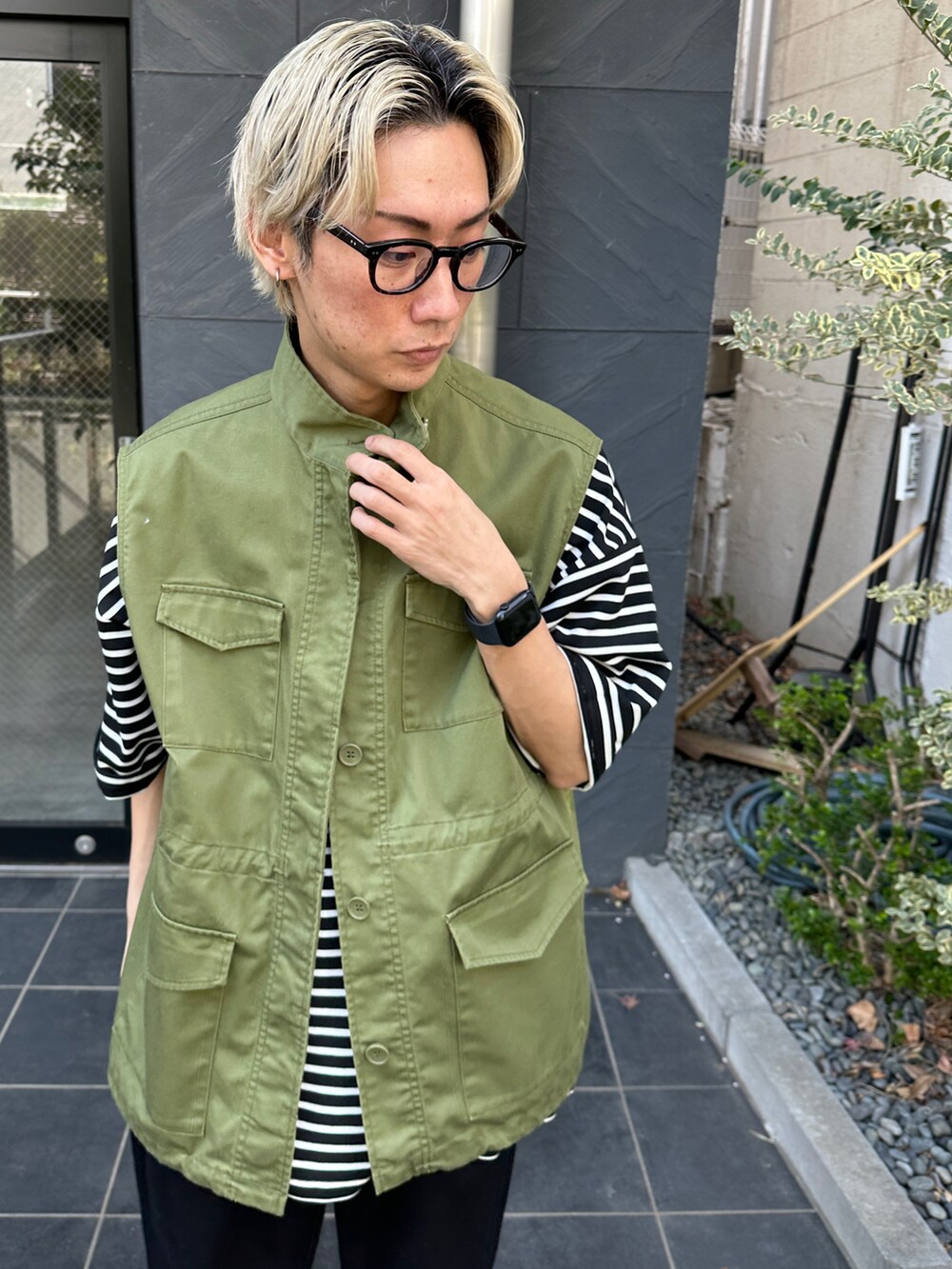 グリーン系のベスト、ブラック系のTシャツ/カットソー、ブラック系のチノパンツを着用したメンズの春コーディネートの4枚目の写真